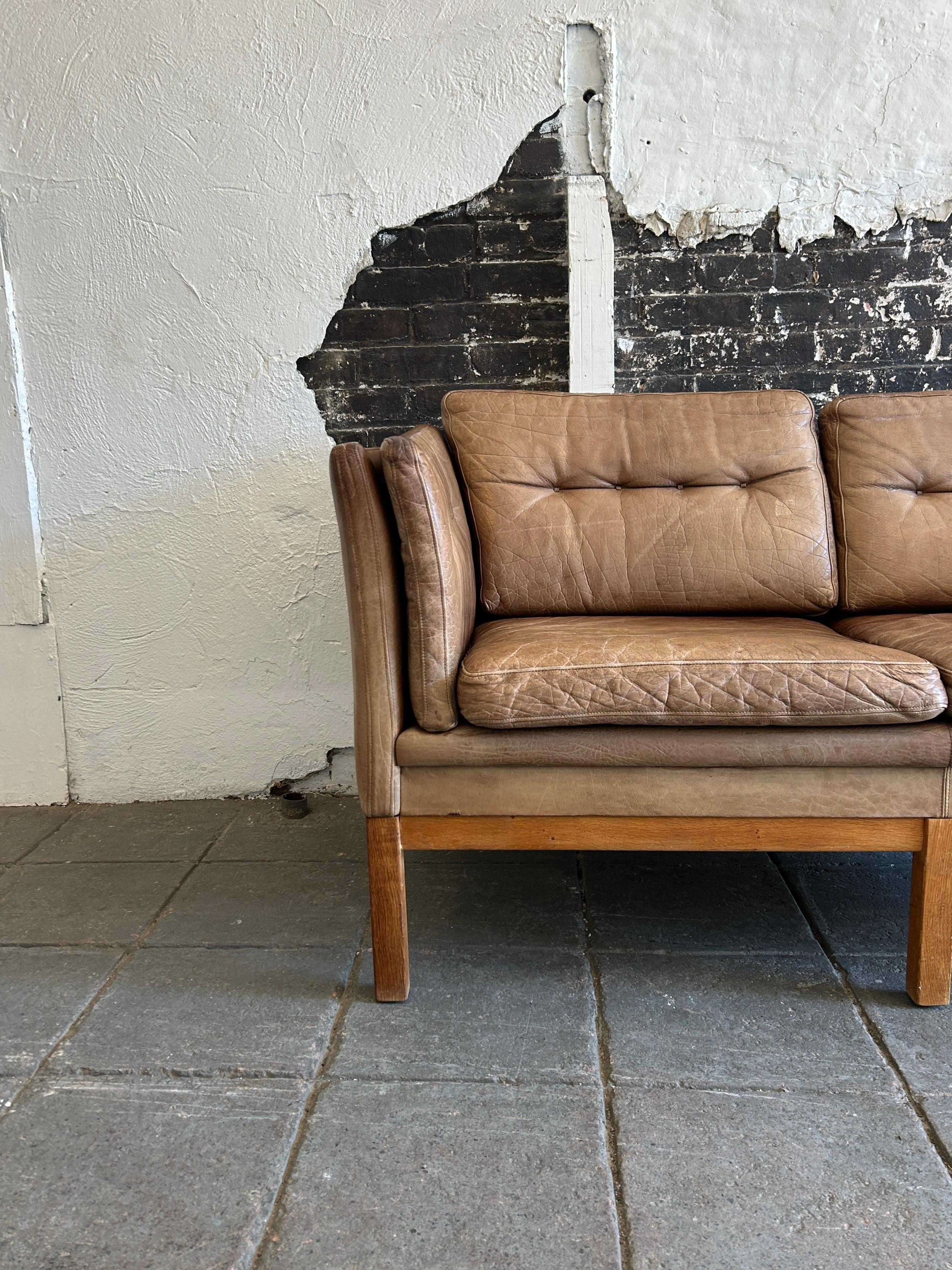 Mid century Danish modern Brown leather 2 seat sofa that sits on an 6 leg solid white oak base. Made by Skippers mobler. Light Brown leather is soft and shows lots of patina fading and signs of use but broken in nicely. Great small Danish Modern
