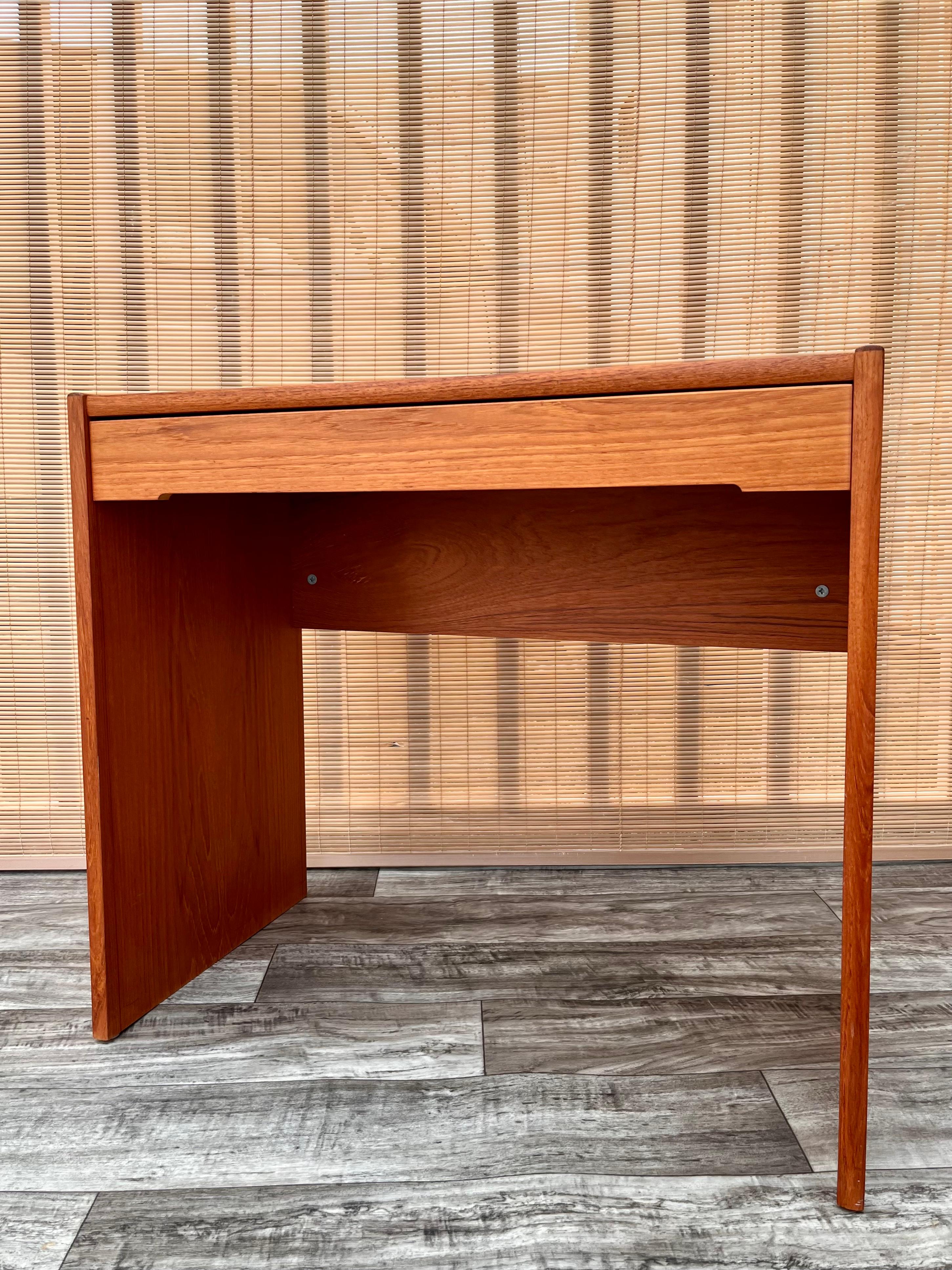 Vintage mid-century Danish Modern compact secretary desk. Circa 1970s.
Features a minimalist Danish Modern Design, a beautiful teak wood grain finish, a side to side drawer, and the perfect size for to fit in any small area or room. 
The back of