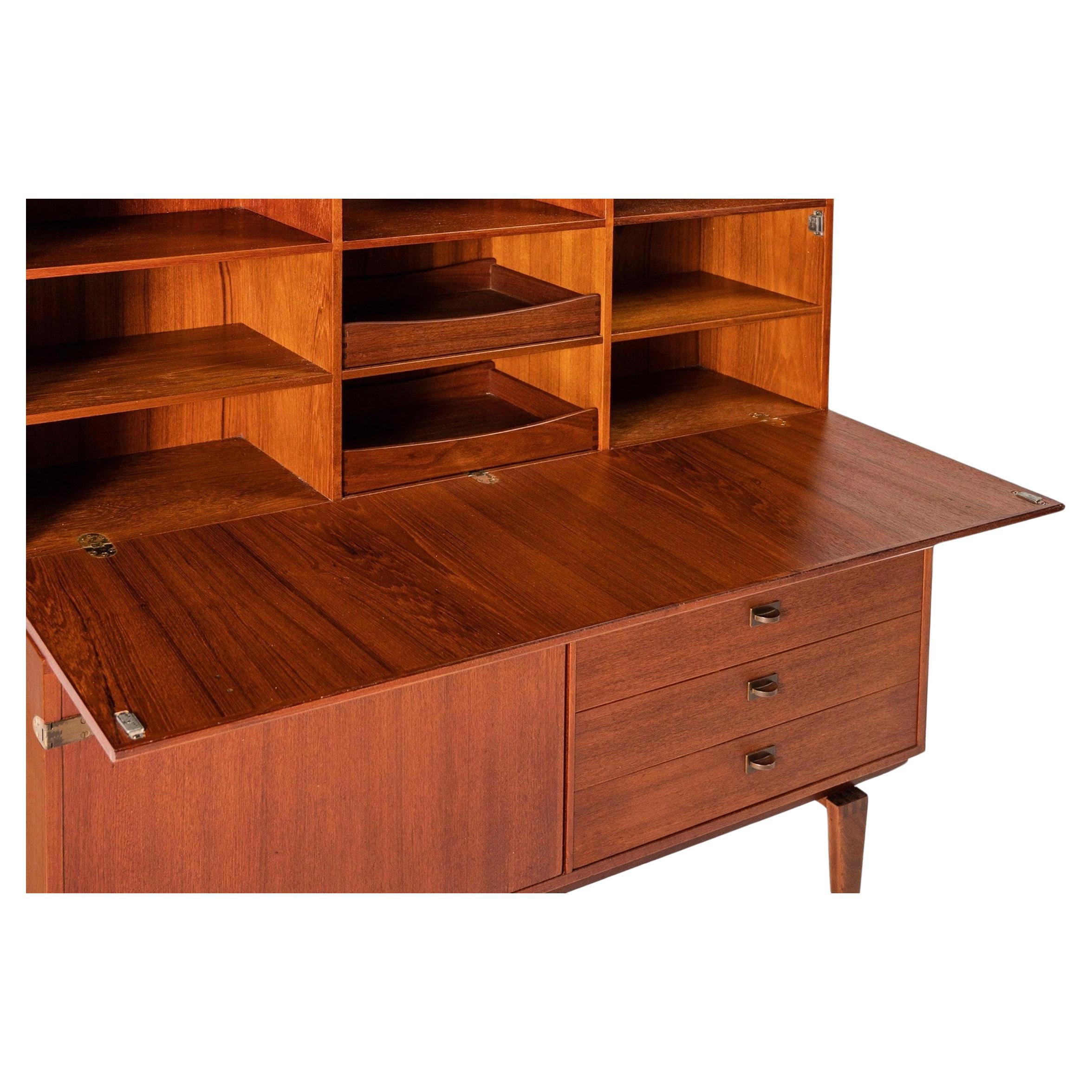 Beautiful mid century Danish modern credenza with flip down desk and shelf unit designed by Lovig for Dansk. Nice flip down desk area with cubbies and drawers. Teak upper bookcase unit with shelves on top of lower teak credenza with one cabinet door