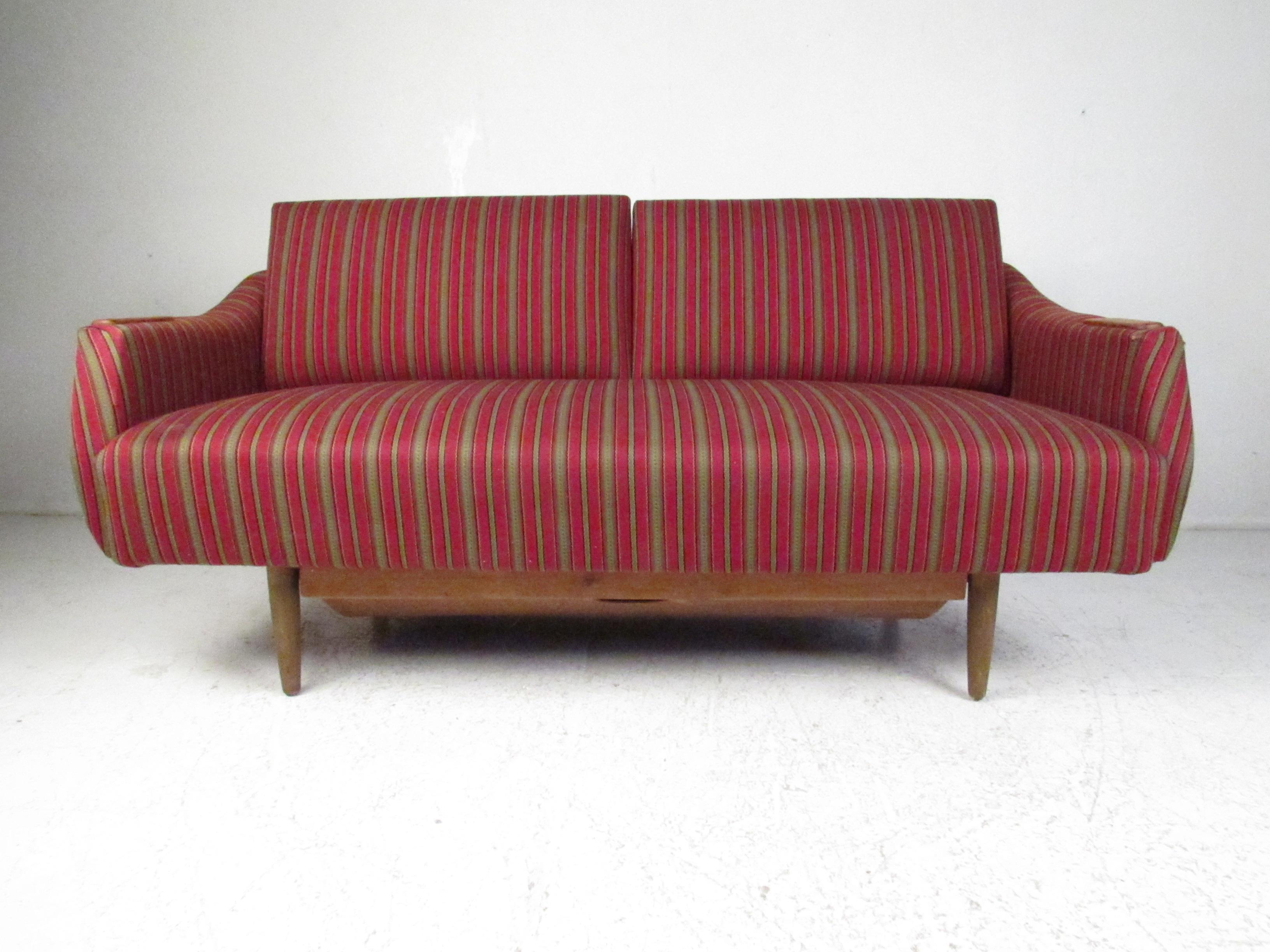 This beautiful vintage modern daybed was designed in the style of Peter Hvidt. A stylish and comfortable sofa with armrests that drop down on each side. This unique Danish modern sofa has a hidden drawer underneath to store additional items