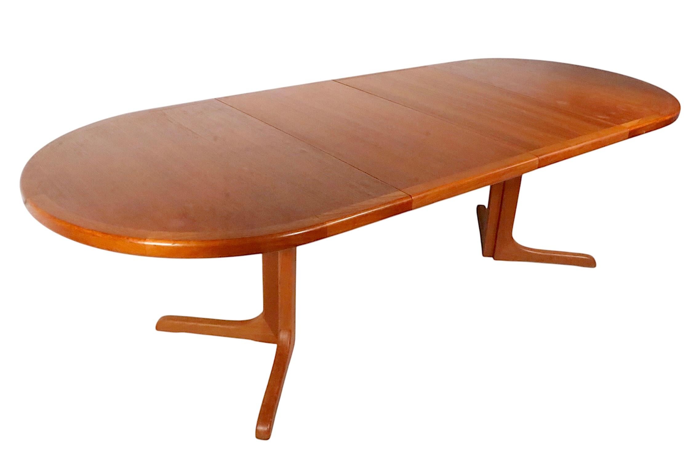 Mid Century Danish Modern dining table with two leaves, attributed to Glostrup Mobelfabrik, c. 1960/70's. The table feature a split pedestal base, which separates into two parts when the table is open  to accept leaves. This example is structurally