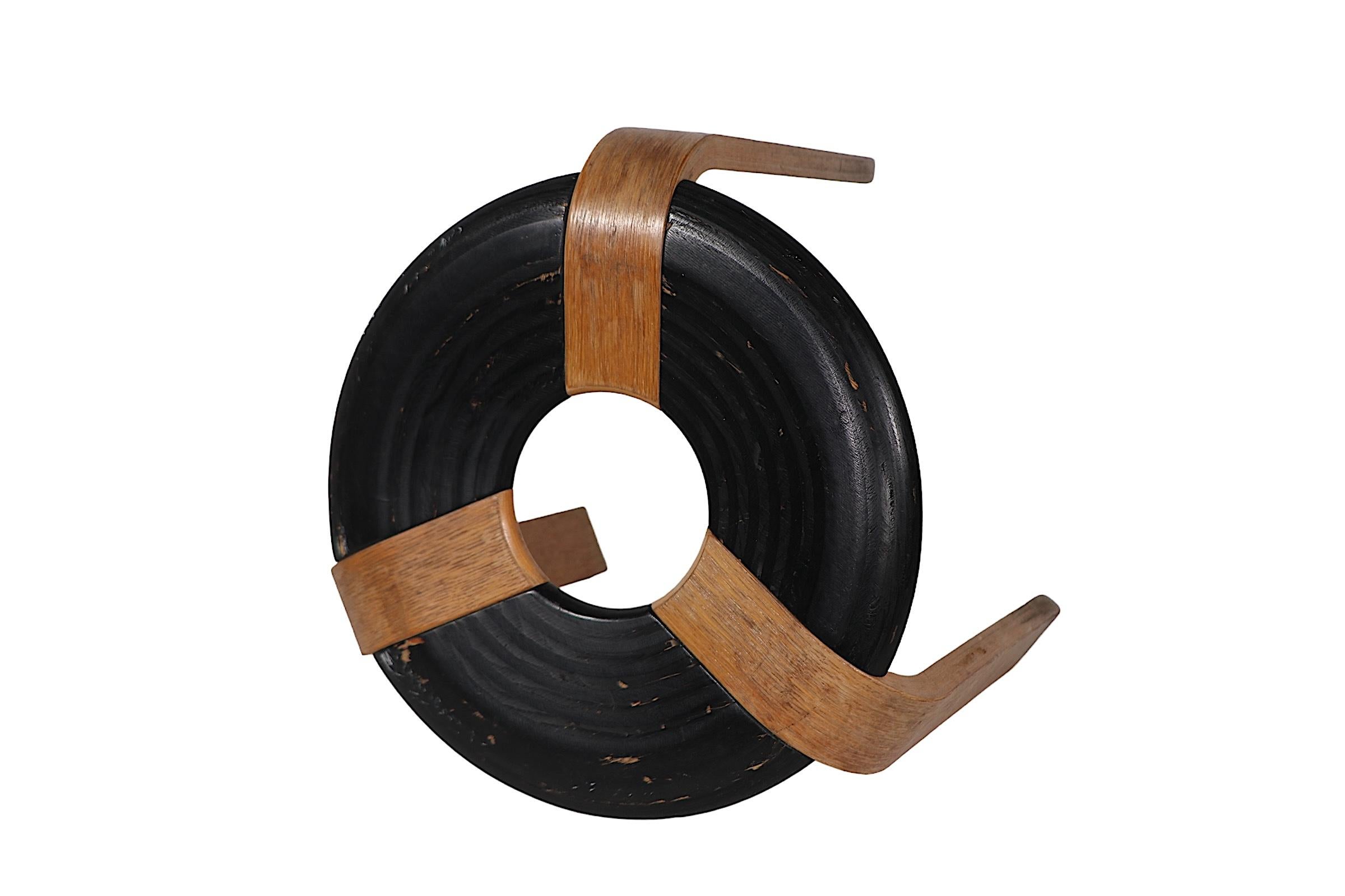 Iconic Danish Modern design stool by Rud Thygesen and Johnny Sorensen for Magnus Olsen circa 1970's. The stool features three bent laminate wood legs, attached to an ebonized donut form seat, it retains its original foil label on verso, as shown.
