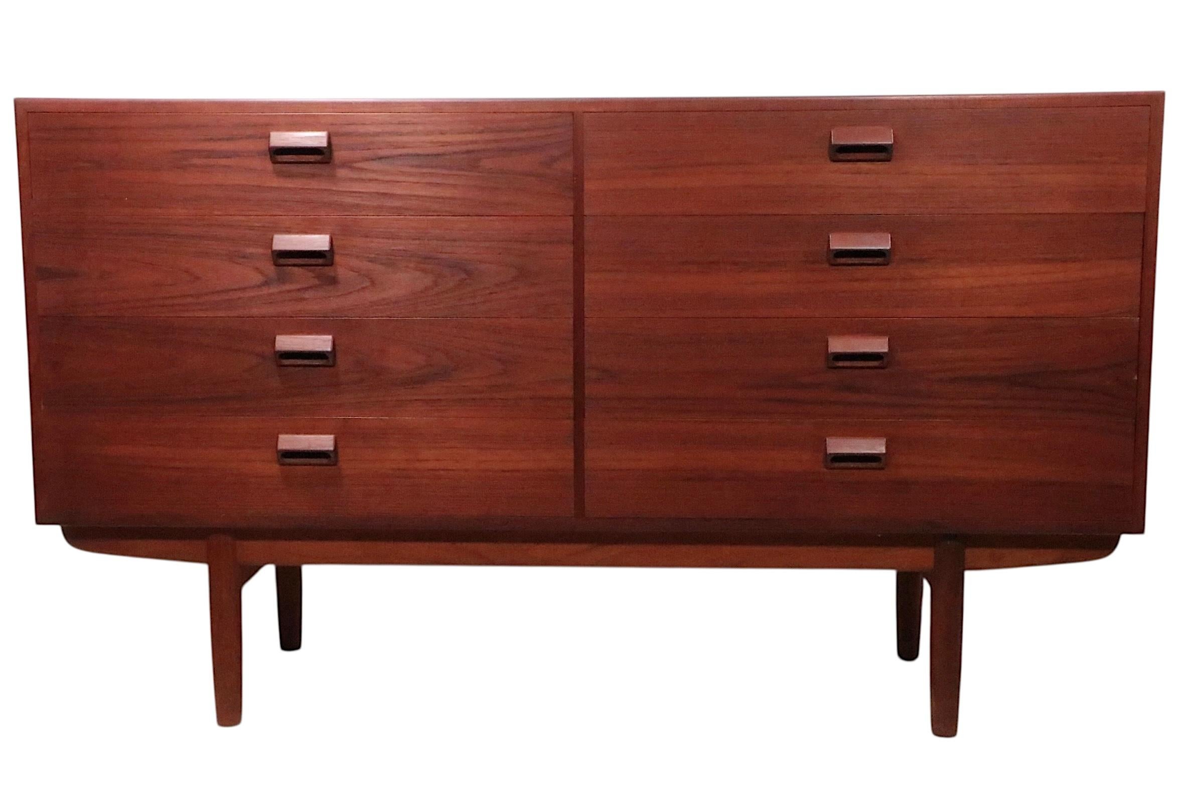 Iconic Mid Century Danish Modern eight drawer dresser, designed by Borge Mogensen, made by Soborg Mobelfabrik, circa 1950's. The cabinet is constructed of teak with blonde wood, probably birch, drawer interiors. This example is in very good,