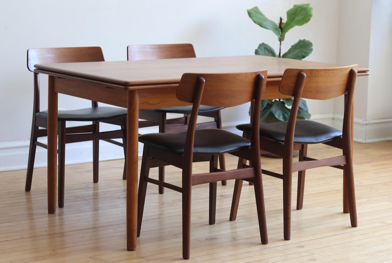Mid-Century Modern Danish teakwood dining table and 5 chairs.
Just imported from Denmark.
Refinished table features large self-storing leaves on each end.
Includes five Scandinavian chairs with new black vinyl upholstery and new foam