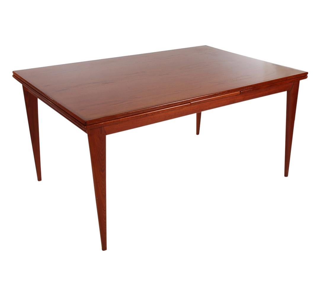 This is a large and impressive dining table designed by Niels Otto Møller in the 1960s. It is well constructed of teak with absolutely stunning wood grain. It features two self storing leaves. It extends to 105 inches in total width. Restored