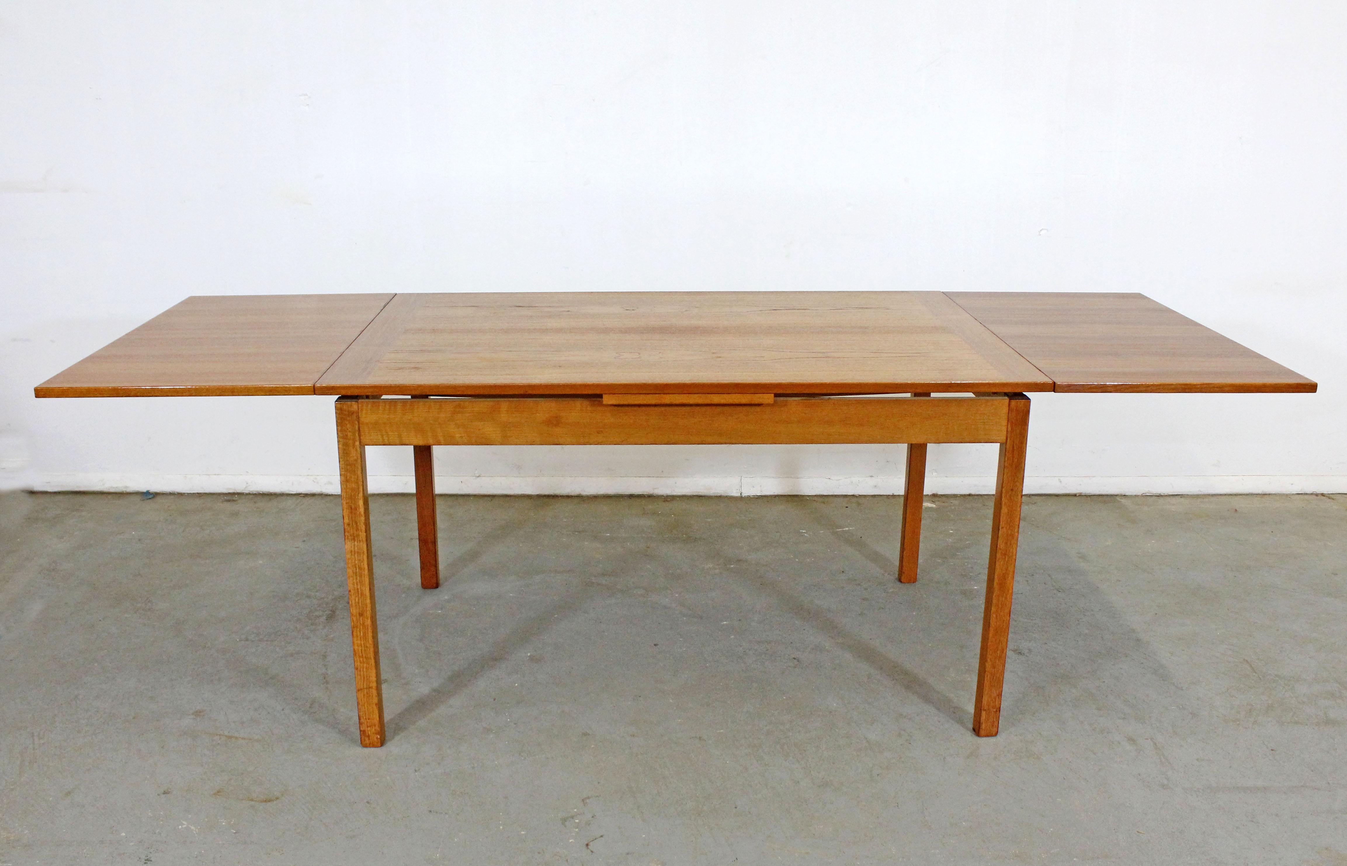 Offered is a vintage Danish modern extendable dining table. This is a teak dining table with two extension boards that pullout / pull-out from the sides. It is in good condition, has been refinished, showing slight age wear (blemish/imperfections in