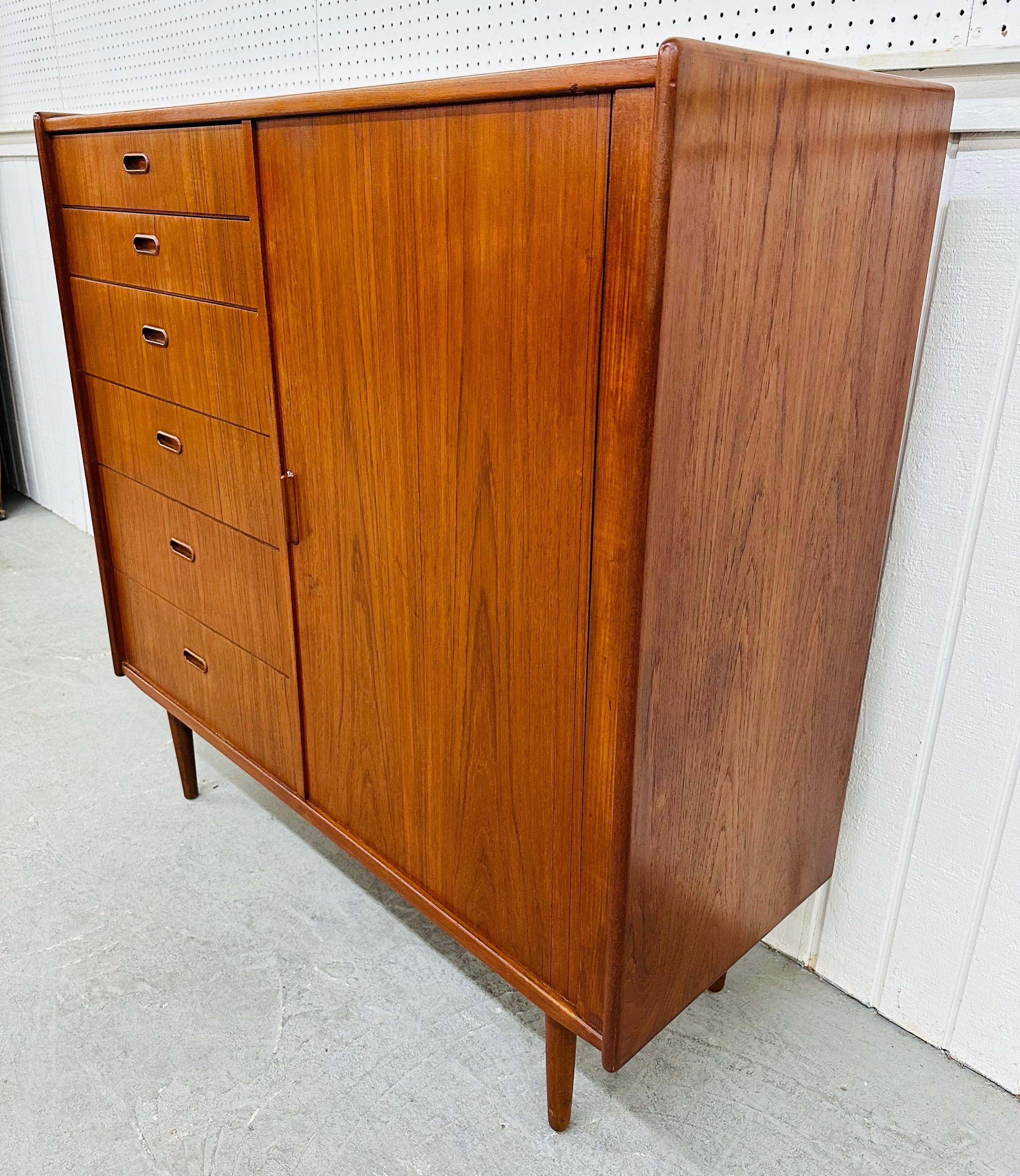 This listing is for a Mid-Century Danish Modern Falster Teak Tambour High Chest. Featuring a straight line design, six graduated drawers on the left side, recessed wooden pulls, tambour sliding door on the right that opens up to six hidden drawers,