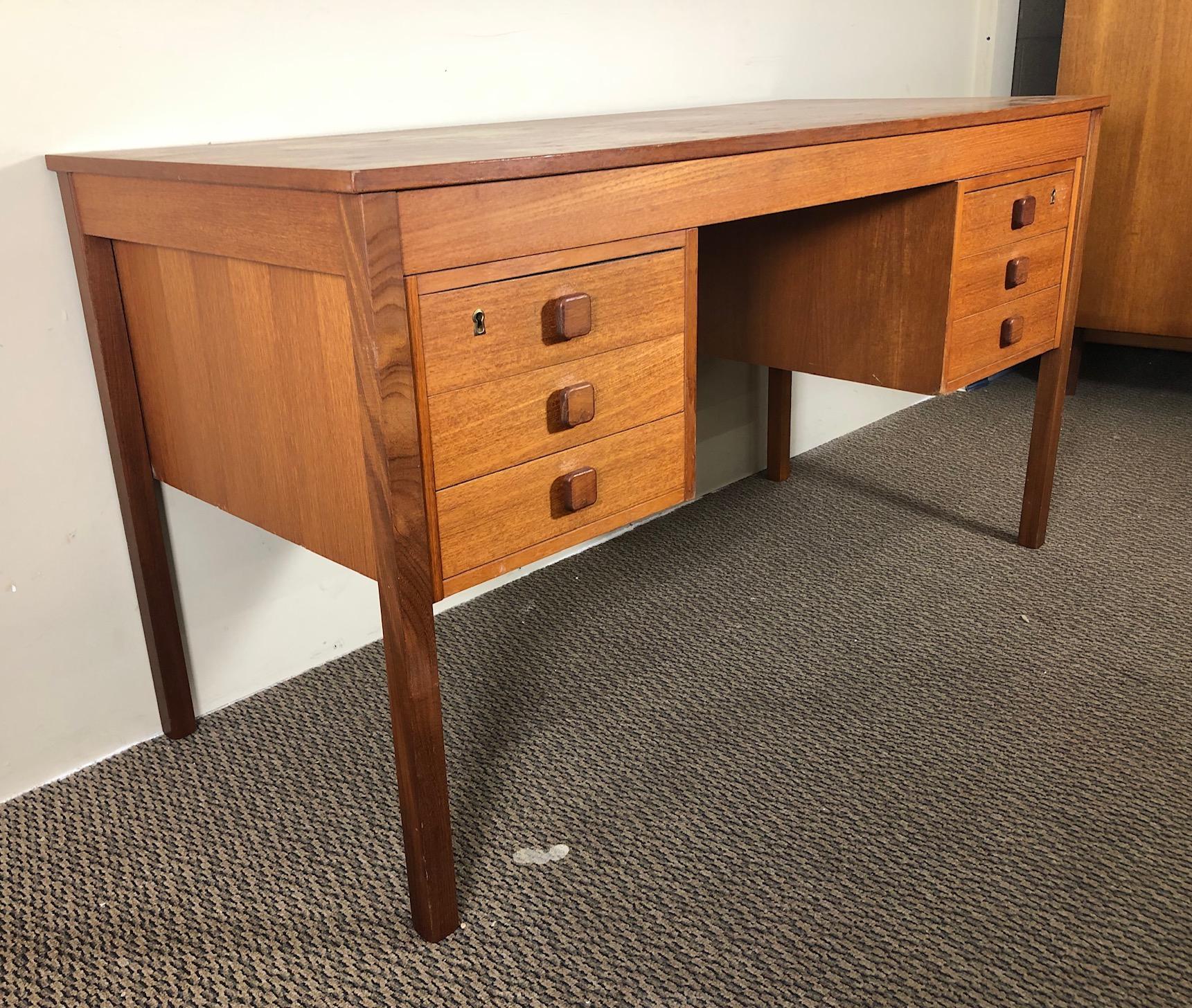 Nice Mid-Century Modern teak desk. Made in Denmark.

This is a free standing desk with a finished back.

Featuring 3 drawers on the left and on the right. It has a lock but no key.

The desk is in very good vintage condition. There is some