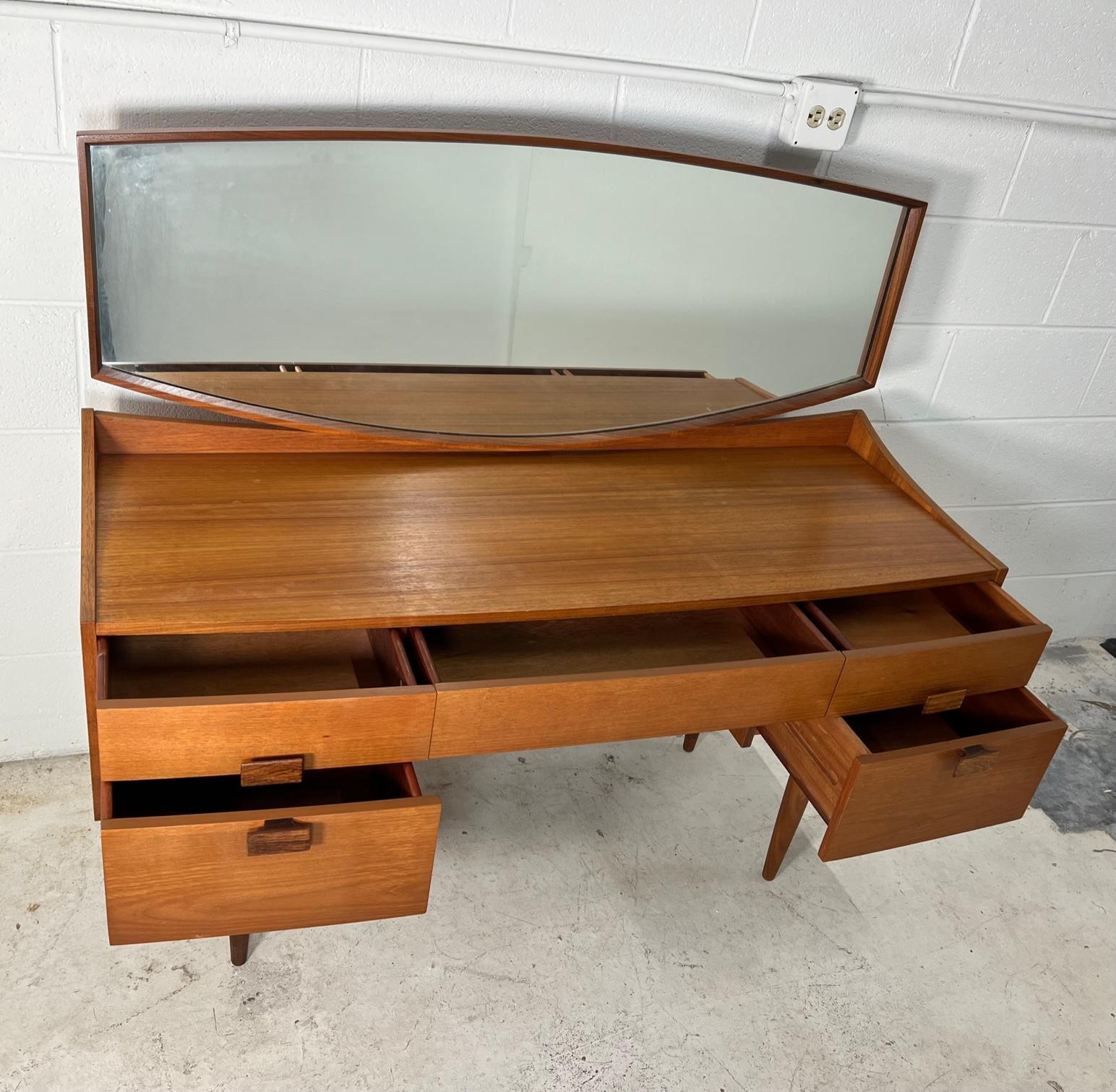 Fantastic midcentury teak veneer vanity with mirror. Designed by Danish designer Kofod-Larsen. Made by G Plan.
Features Kofod-Larsen's signature split handle design on the drawers. The handles are stained rosewood.

Very good vintage condition. All