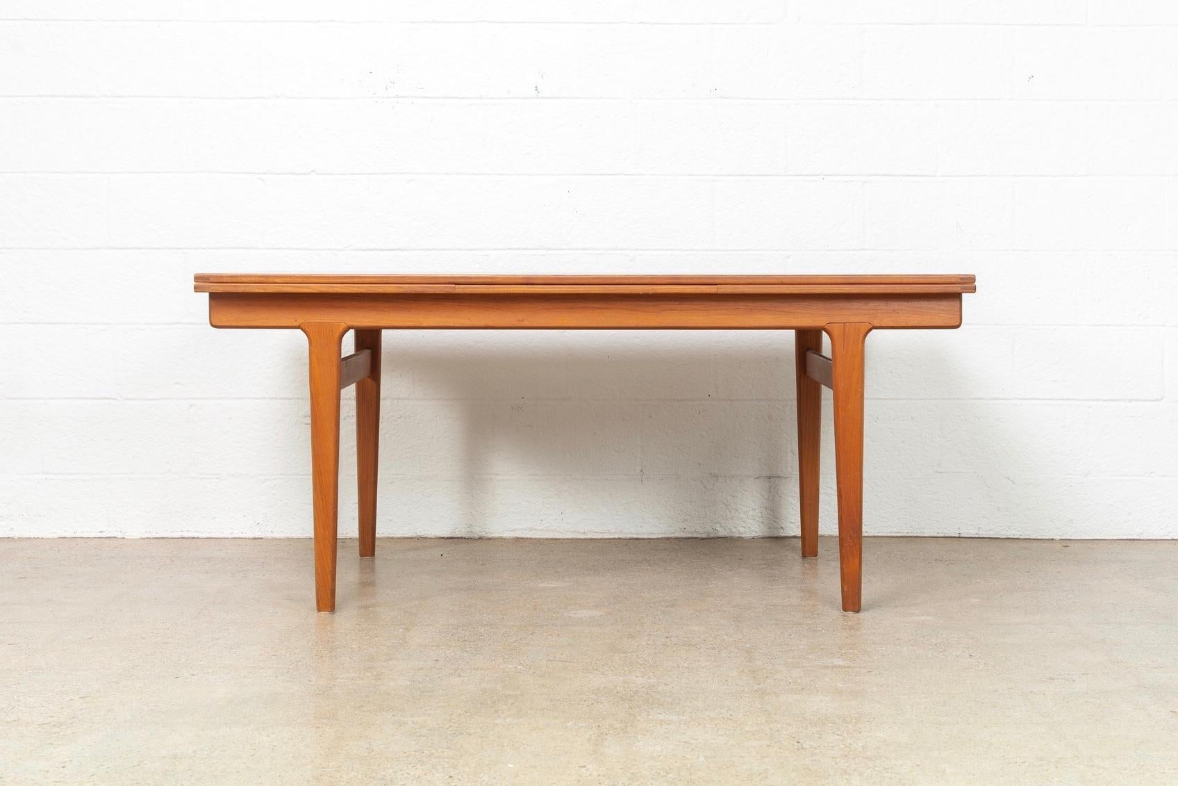This vintage Mid-Century Modern Henning Kjaernulf for Vejle Moebelfabrik expandable dining table made in Denmark circa 1960 has an elegant Minimalist aesthetic and a clean, unimposing Danish modern design. It is exceptionally crafted from solid teak