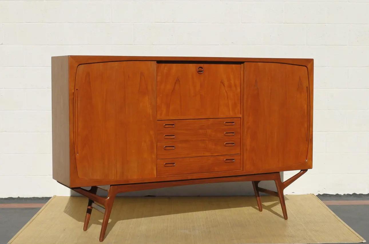 Ce buffet haut danois pour cocktails a été conçu par Kurt Ostervig, vers les années 1950 (il n'y a pas de marque de fabrique). Originaire du Danemark, fabriqué en bois de teck, il présente une base de style distinctif avec de magnifiques pieds