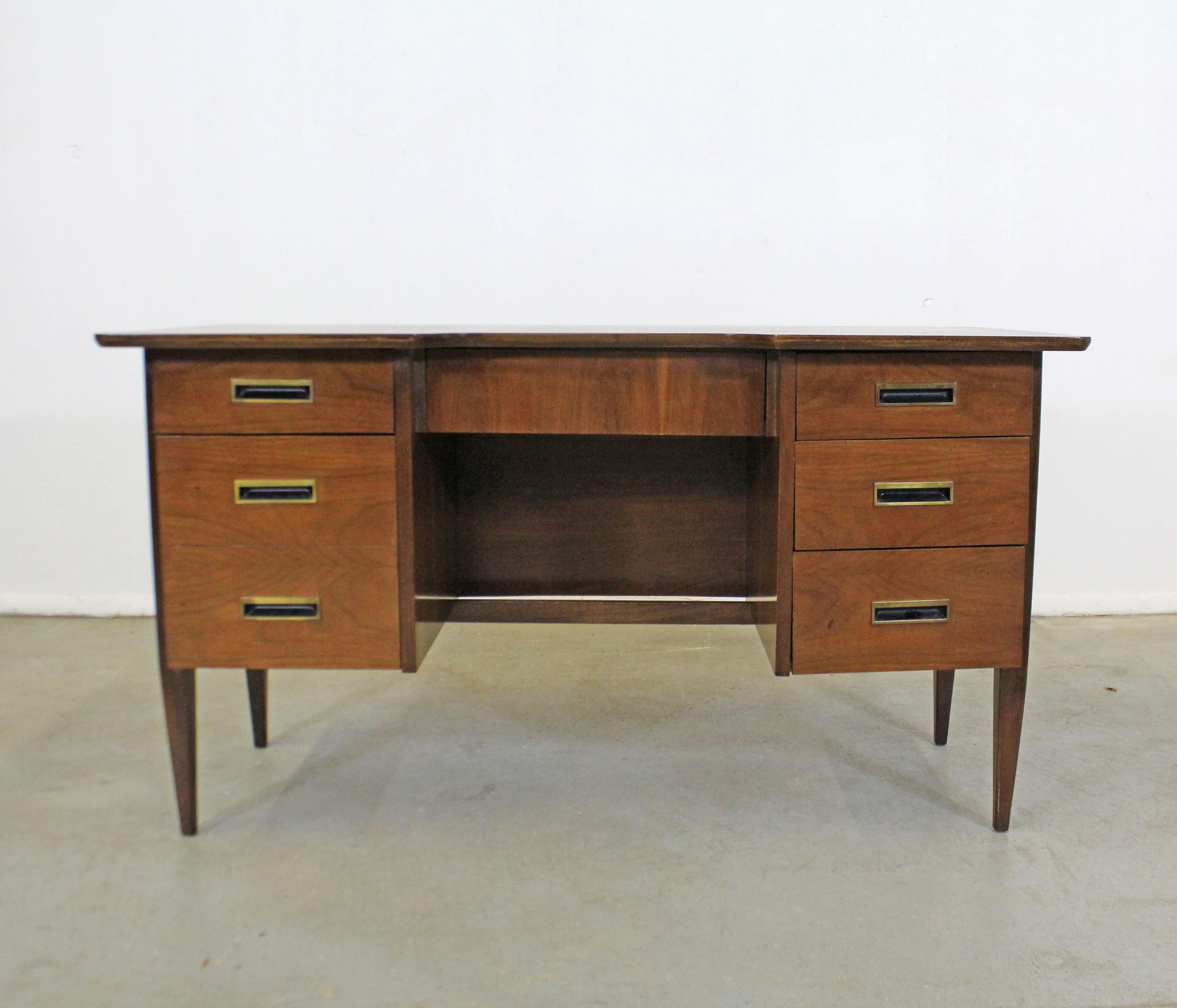Offered is a vintage Mid-Century Modern attributed to Hooker Furniture. This walnut desk has been refinished and features six dovetailed drawers with recessed brass pulls, three on the right, two on the left. See pictures for details. In good,