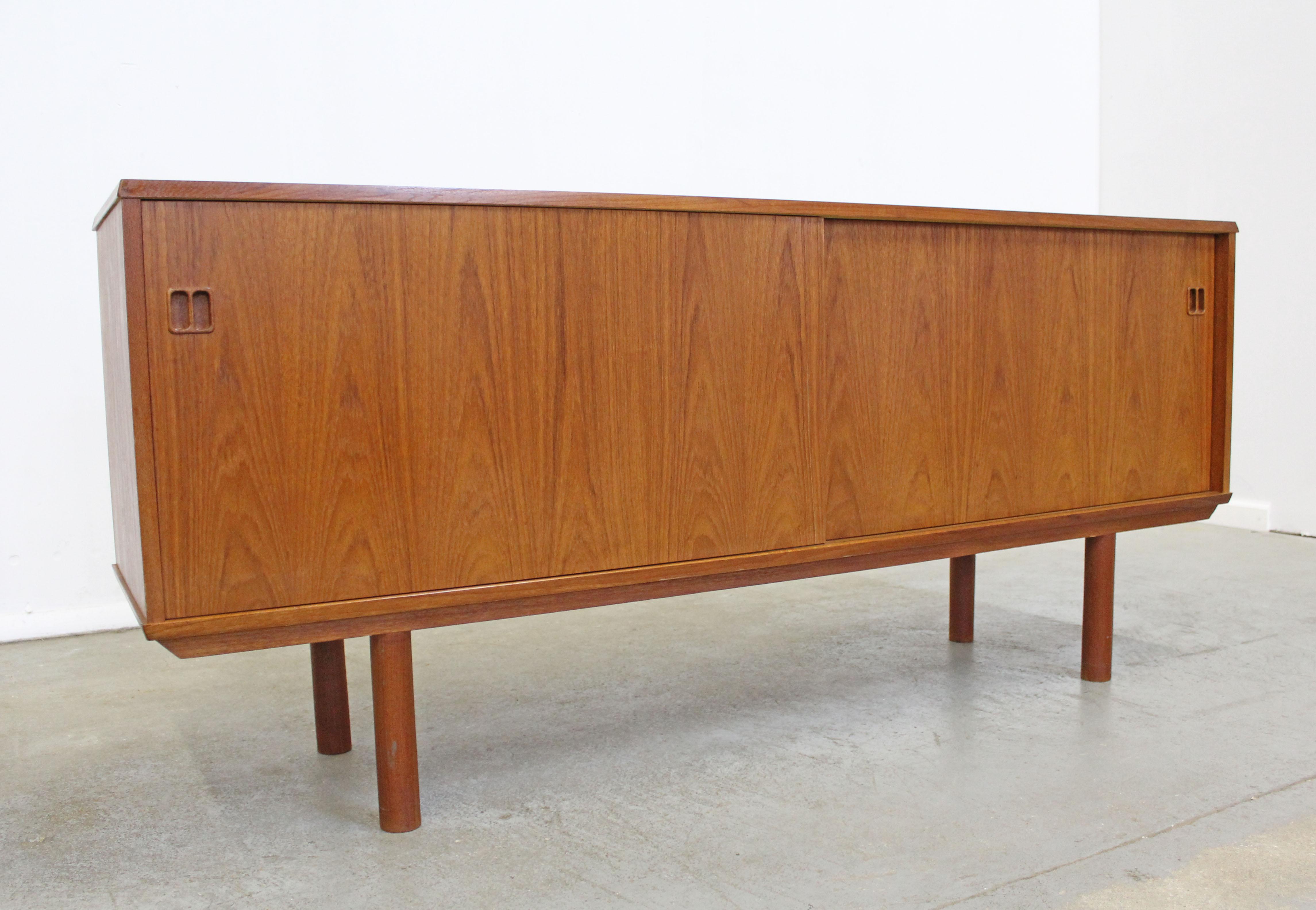 Offered is a Danish modern teak credenza, featuring sliding doors with inner adjustable shelving and 3 drawers on one side. It is in good vintage condition showing some wear (sun fade or discoloration on top, surface scratches, age wear--see
