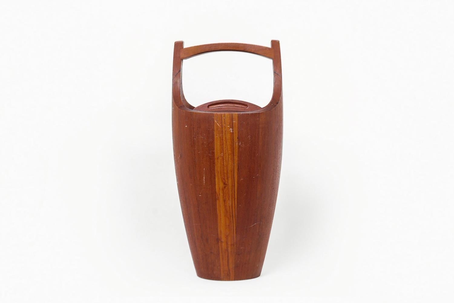 This vintage Danish modern teak ice bucket was designed by Jens Quistgaard for Dansk circa 1950. This earlier model was made in Denmark. The iconic design has a simple and elegant shape featuring a top handle and round removable lid and is made of