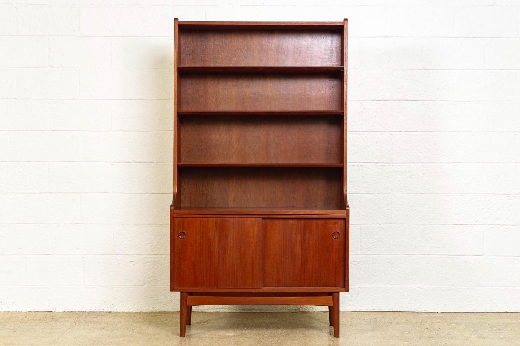 This vintage Mid-Century Modern bookcase designed by Johannes Sorth for Bornholms Møbelfabrik and made in Denmark circa 1960 has a Classic Danish modern design with clean, Minimalist lines. Well-constructed, the tall upper hutch features three