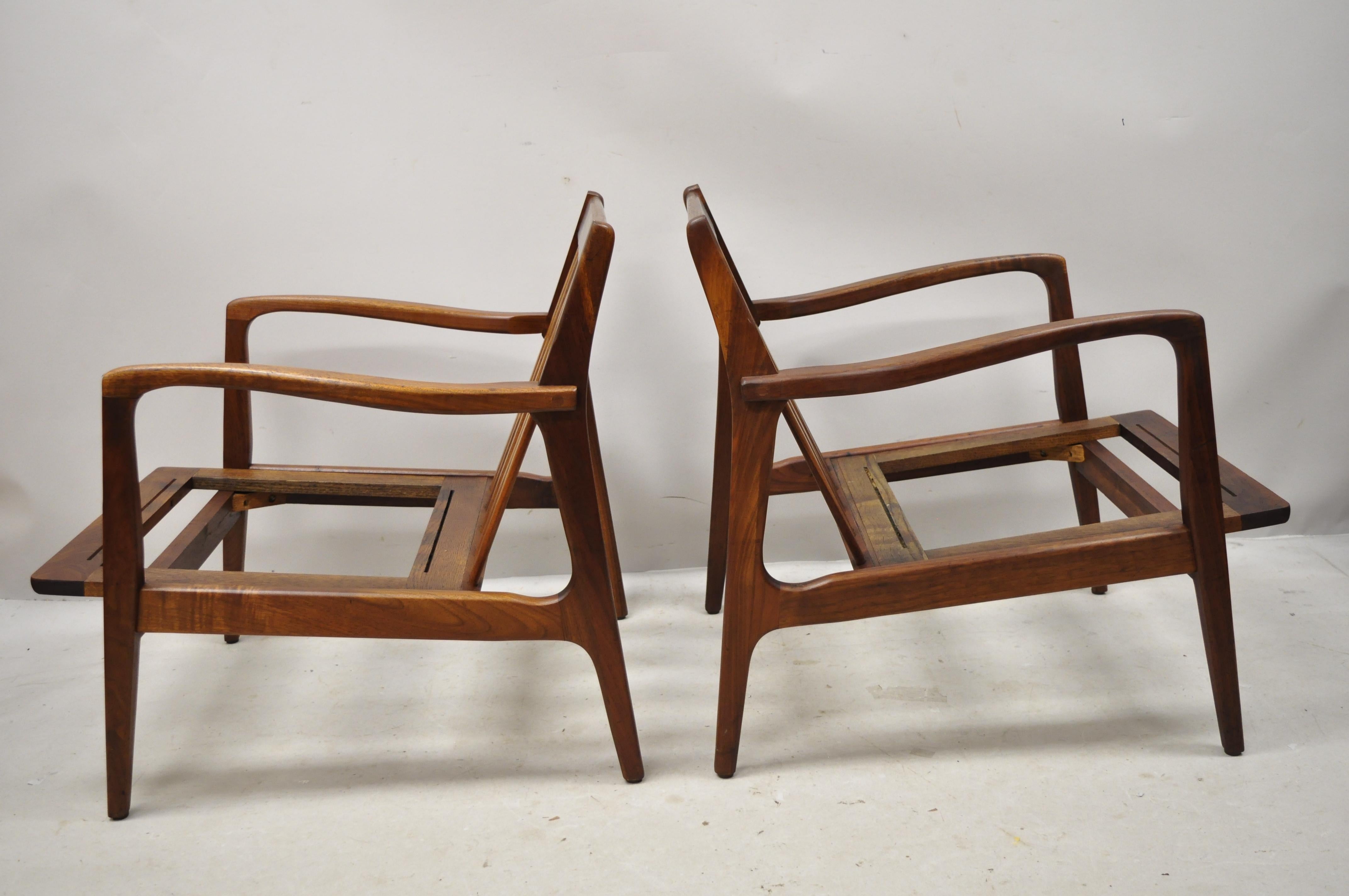 Midcentury Danish modern Kofod Larsen style walnut lounge chairs - a pair. Item features a solid wood frame, beautiful wood grain, clean modernist lines, sleek sculptural form, circa-mid 20th century. Measurements: 28