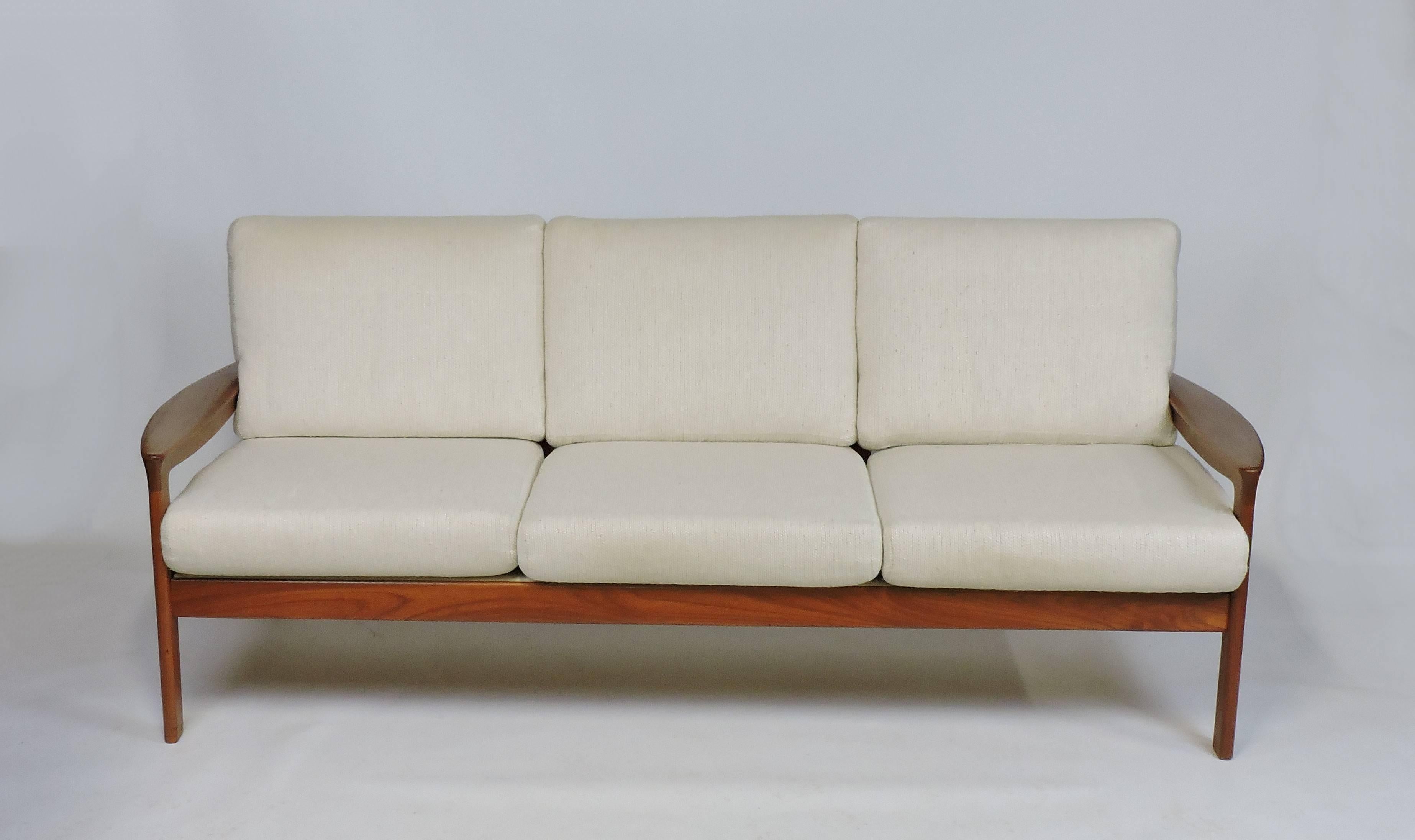 Beautiful and comfortable three-seat sofa made by Komfort of Denmark. It has great craftsmanship with a sculpted solid teak frame with paddle arms, and a slat back. The zippered cushions have the original off-white textured upholstery. Marked with a