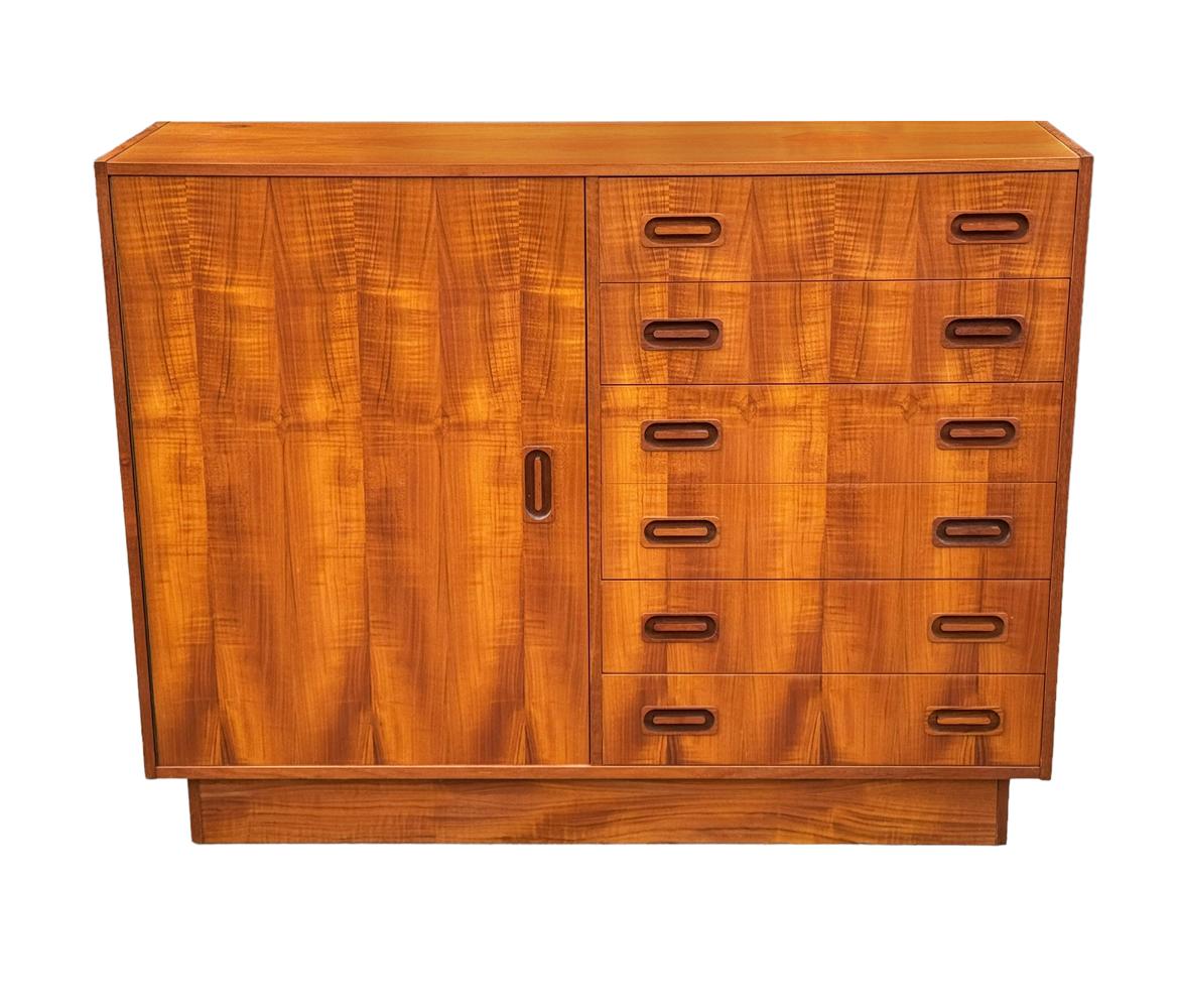A stunning Scandinavian cabinet from the 1960's. This sleek piece features gorgeous book-matched teak wood, large door and six drawers with tons of interior storage space. Nice shallow depth. 