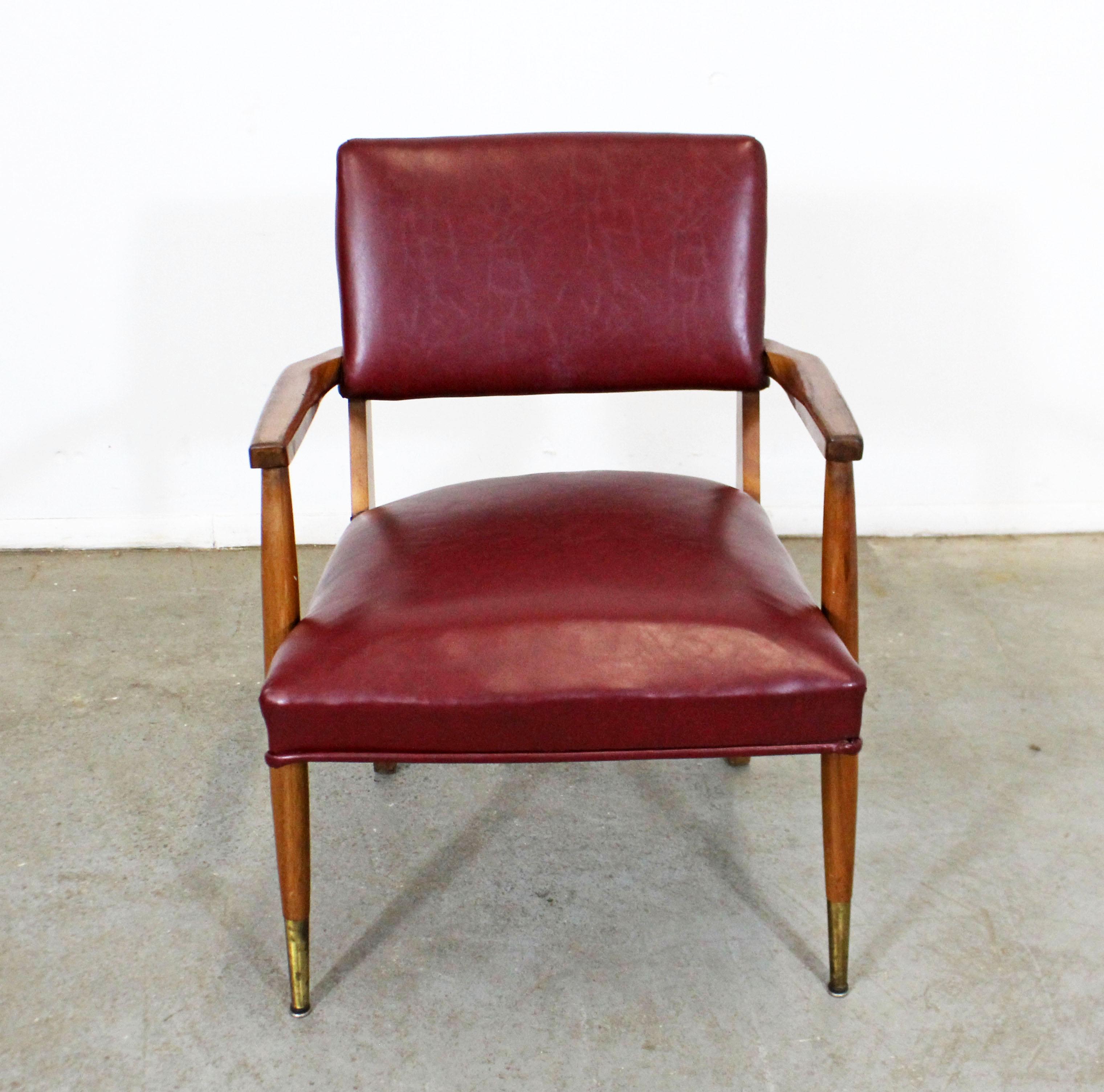 What a find. Offered is a comfortable vintage Mid-Century Modern arm chair with a wood base, brass feet, and faux leather upholstery (made circa 1950-1960). It is in good condition with normal age wear - surface wear or scratches, some separation at