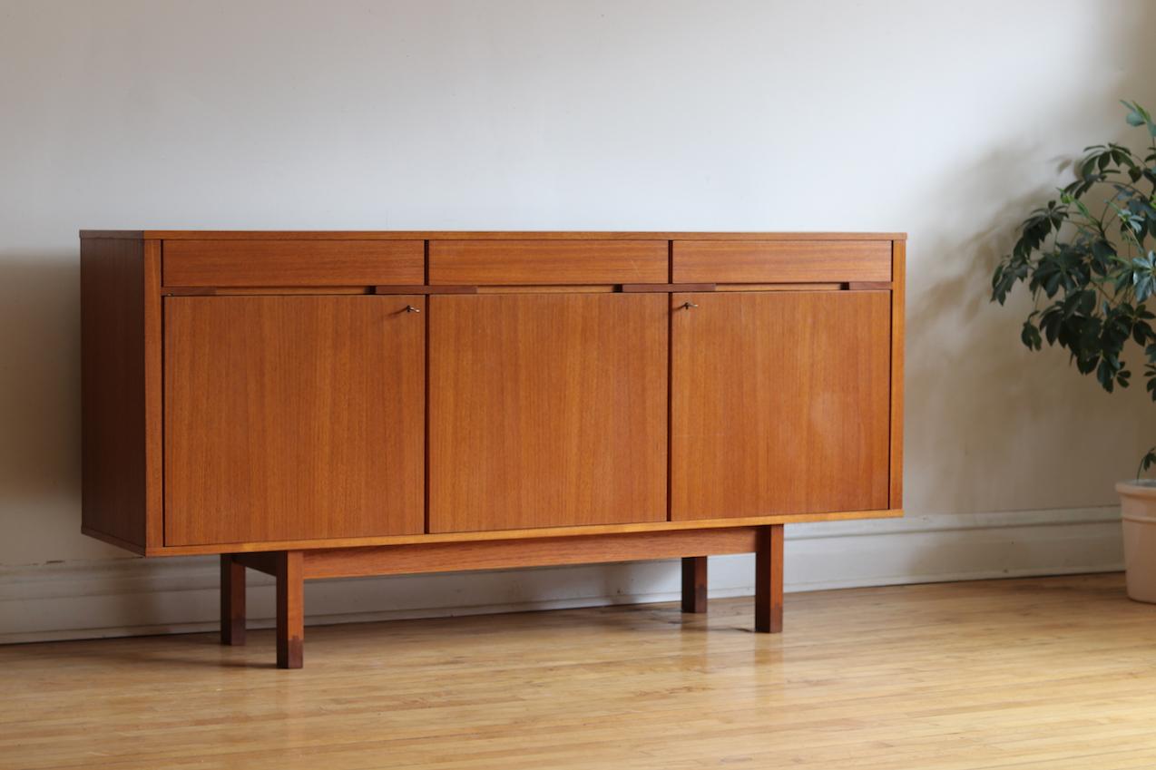 Mid-Century Modern Danish locking teak wood sideboard.
Just imported from Copenhagen.
A few inches taller than the average credenza.
Legs feature a darker wood dovetailed inlay. 
Includes two vintage keys. 
Unique design details