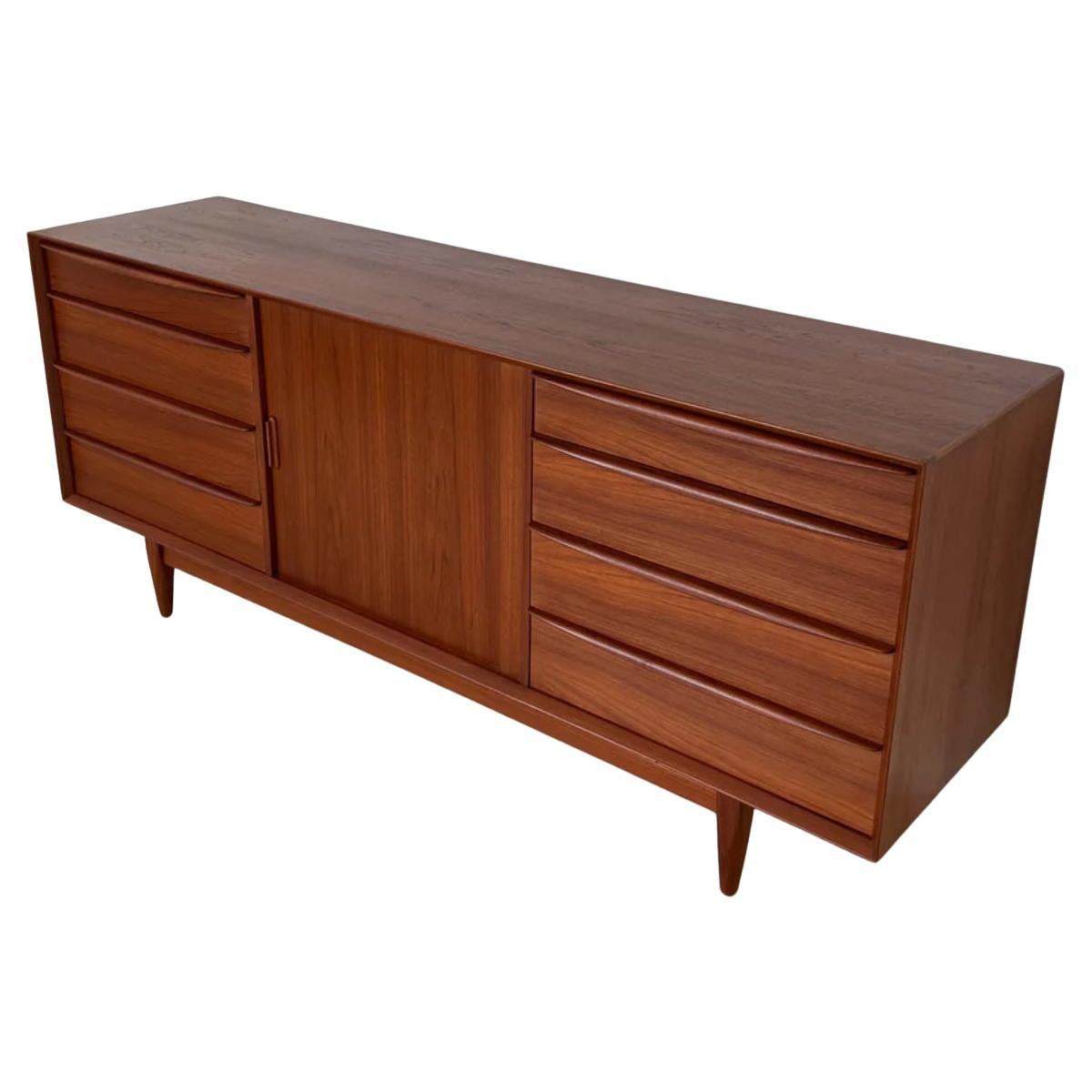 Mid century Danish Modern low long teak dresser credenza by Svend Aage Madsen for Falster. This beautiful credenza has 4 drawers on left and right. Has center cabinet door with 5 drawers behind the Tambour door. Very clean all around inside and out
