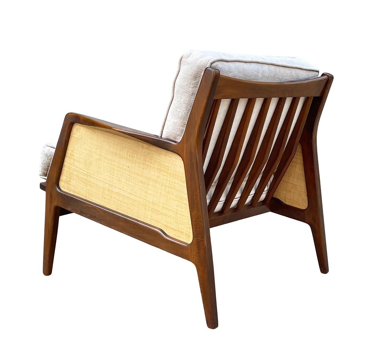 A rare & early lounge chair designed by IB Kofod-Larsen and produced in Denmark, ca. 1950's. It features solid walnut framing, grasscloth side panels, and white seat cushions. Cushions were recovered at some point.
