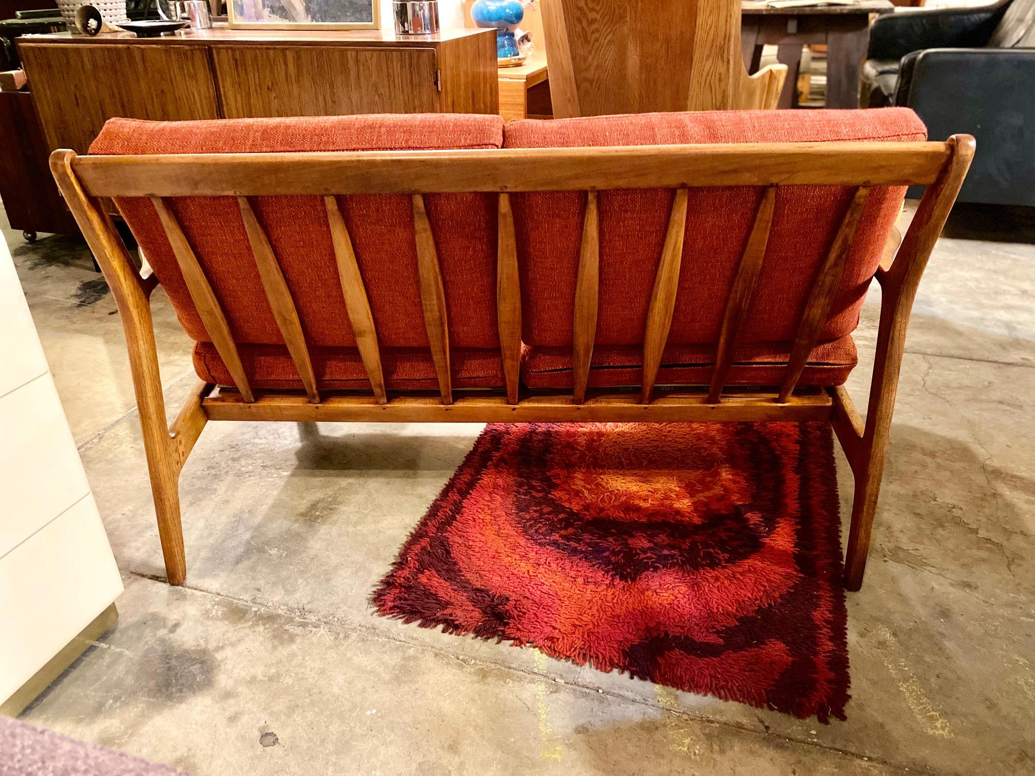 Mid-Century Modern sculptural loveseat by Baumritter. This loveseat with walnut frame features removable cushions, slanted slats for comfort, and is in great condition. Mid-century loveseat is perfect for seating in a bedroom, office, or for any