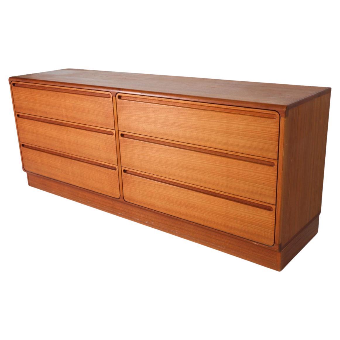 Mid century danish modern low teak dresser by Nils Johnson. Beautiful long low 6 drawer teak dresser with high quality woodworking. Drawers have glides with stops. Curved drawer fronts with inset handles. Has drawer glides with stops. Labeled - 