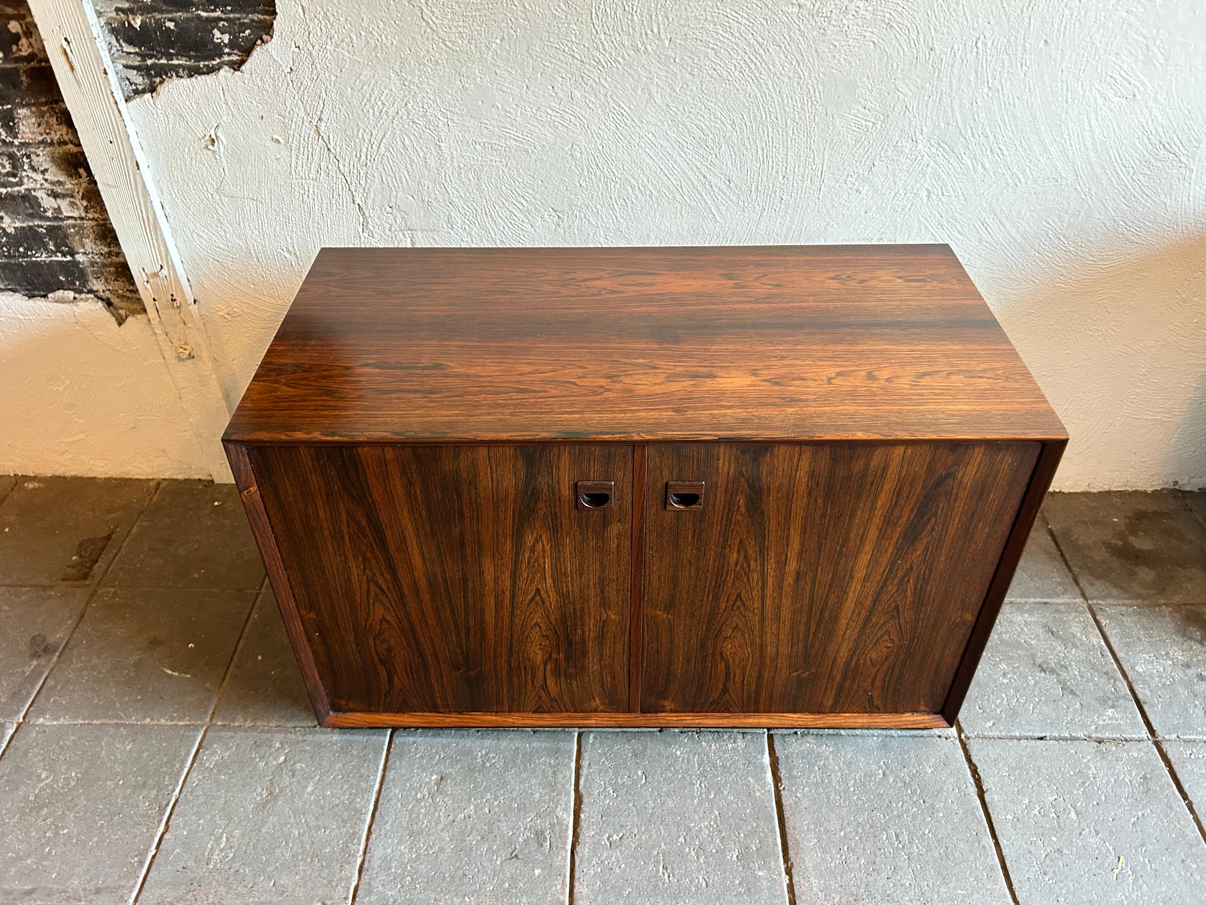 Beautiful mid-century low short Rosewood cabinet credenza 2-door with beautiful carved finger pull handles. In the style of Arne Wahl Iversen. Has 2 adjustable behind the front 2 doors. Clean inside and out all drawers slide smooth on a plinth base.