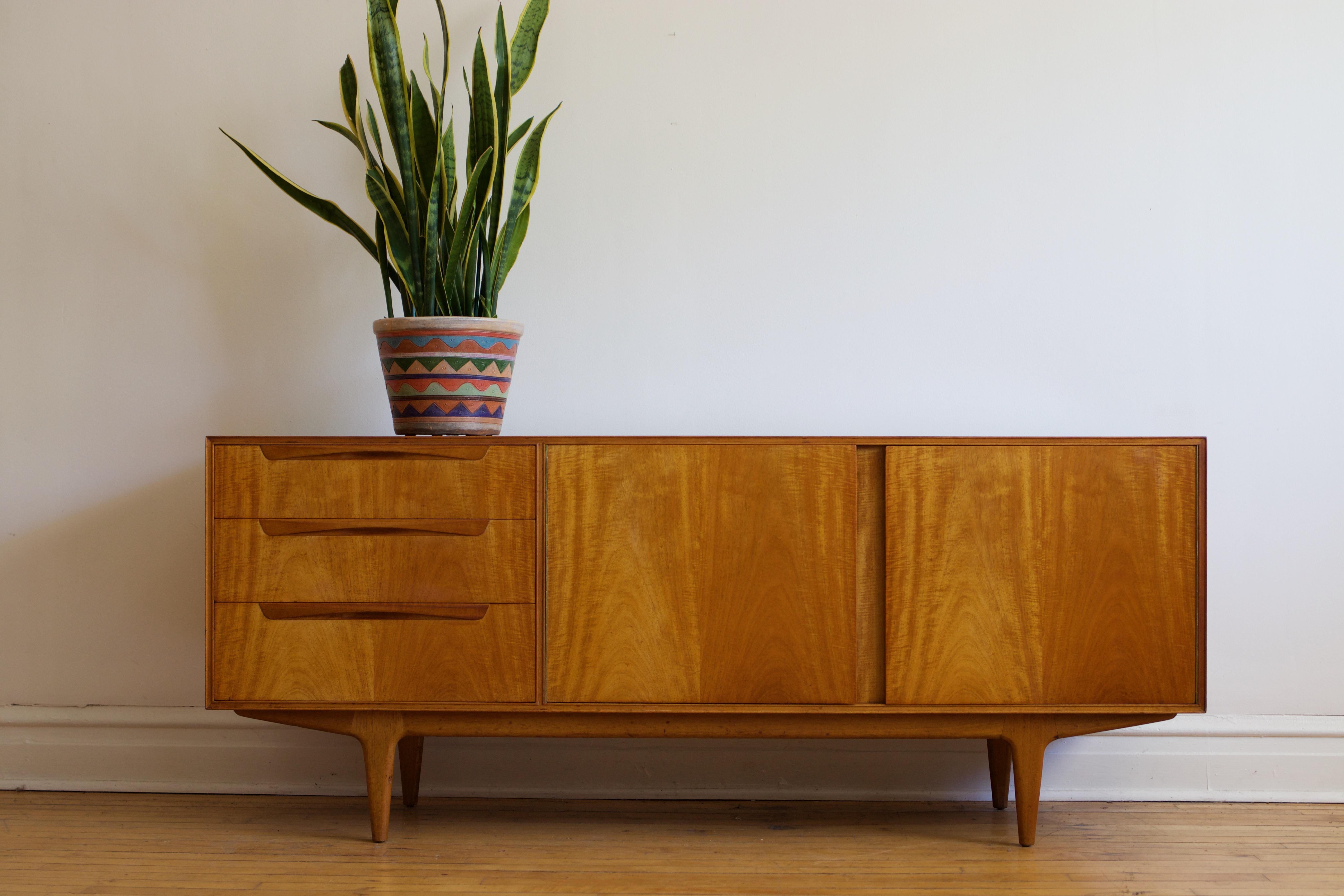 Mid-Century Modern teakwood sideboard.
Just imported from England.
Made in Scotland by McIntosh.
Three dovetailed drawers; top drawer holds dividers.
Double cabinet holds a large shelf.
Great vintage condition.

Measures: 69” long x 17 3/4”