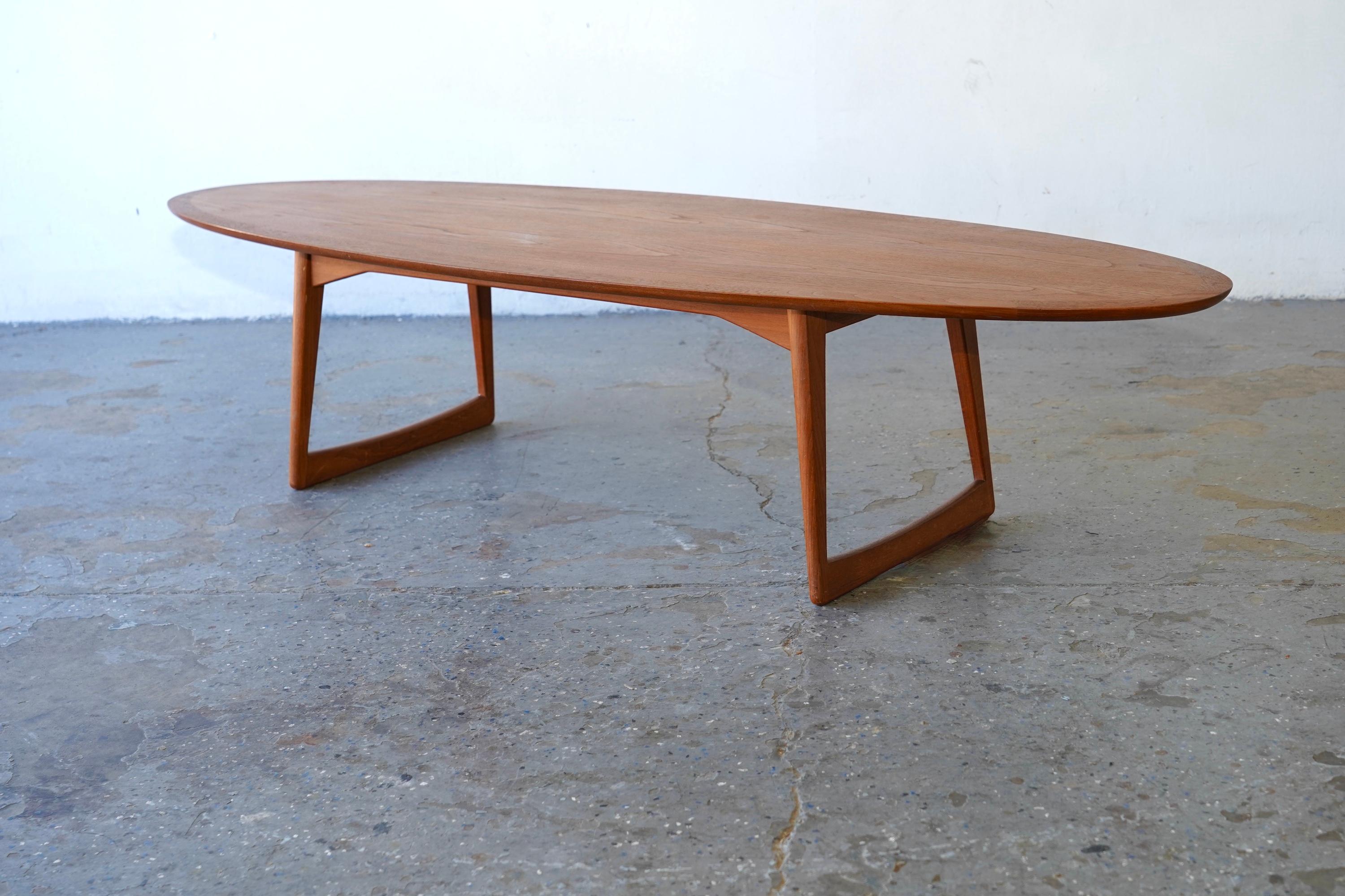 This elegant surfboard-style coffee table was imported from Denmark by Moreddi in the 1950s. Meticulously crafted from teak wood, it features a distinctive sled-style base with slightly angled sculptural legs. The tabletop showcases a rich, warm