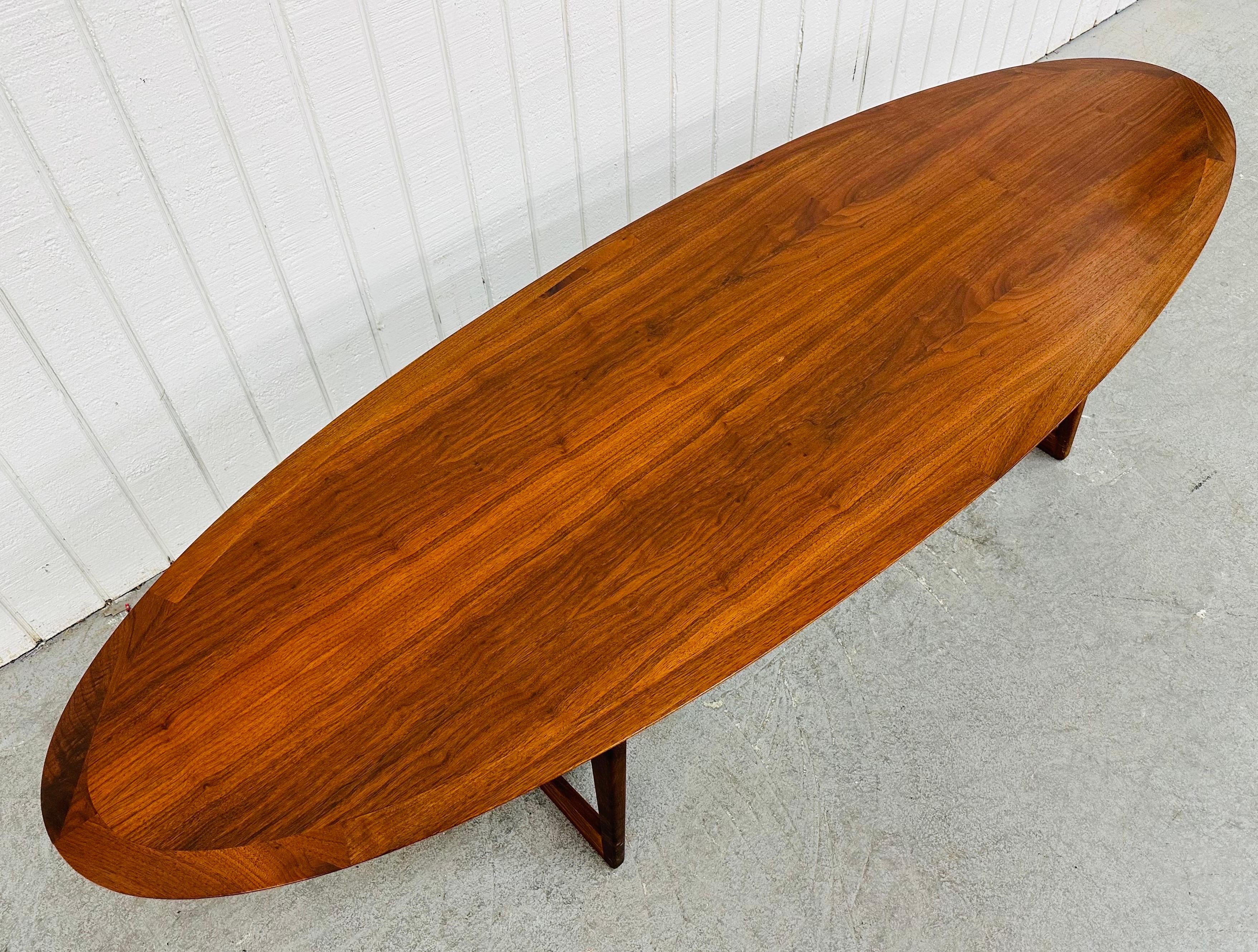 This listing is for a Mid-Century Danish Modern Moreddi Walnut Surfboard Coffee Table. Featuring an extra long oval surfboard style top, modern pedestal style legs, and a beautiful walnut finish. This is an exceptional combination of quality and