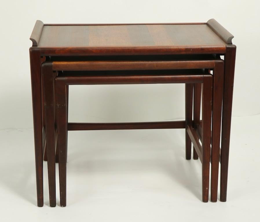 Architectural nest of three tables in solid walnut, with raised trim molding. Well constructed, solid and tight, these tables are in good overall condition, however they do show cosmetic wear, spots and staining to the top surface, and the legs show