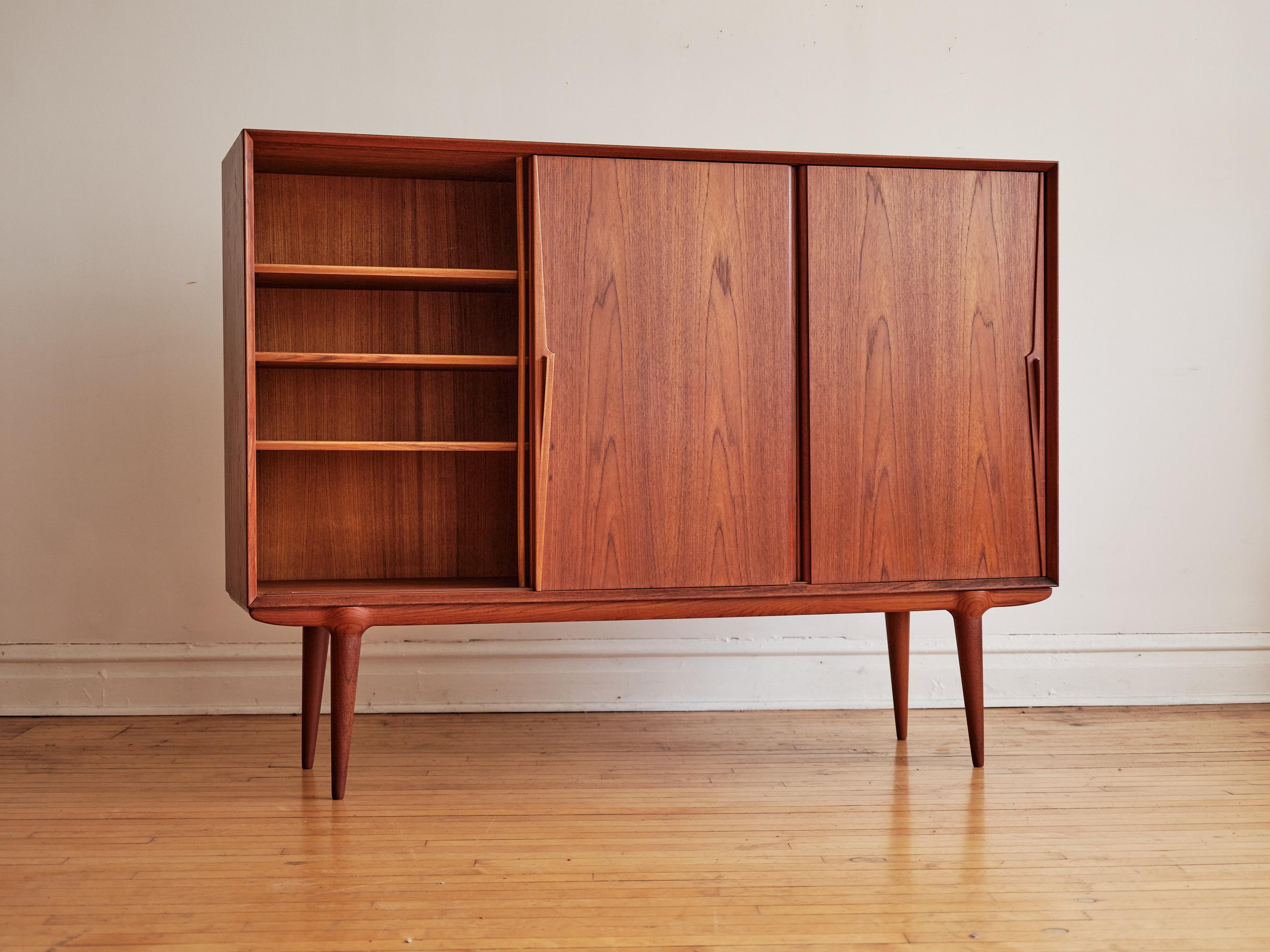 Danish Mid-Century Modern tall teak credenza.
Just imported from Copenhagen.
Model No 15 designed by Gunni Omann for Omann Jun.
Six slide-out dovetailed drawers which double as trays.
Three adjustable shelves.
Finished backside.
Super sleek