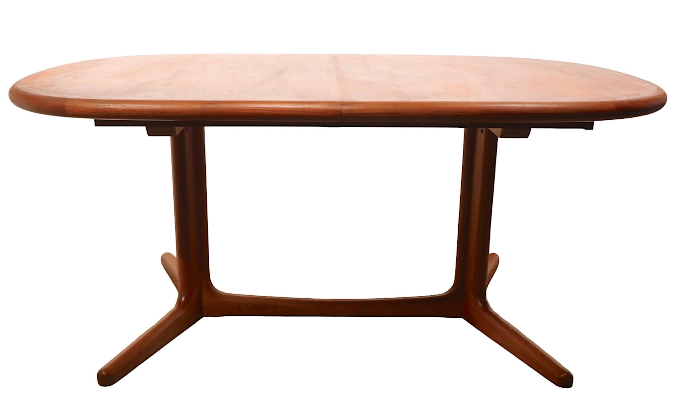 Chic architectural Mid Century Danish Modern dining table by Edvard Valentinsen. The table features an oval top, which opens to accept two large leaves ( 19 in. each ). The base is a sculptural modernist interpretation of the classic trestle base