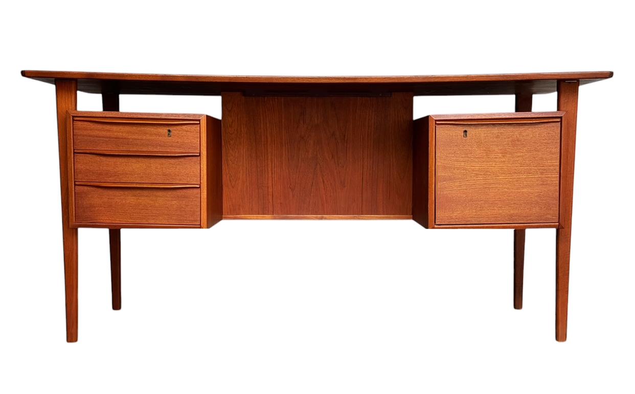 A wonderful and simply designed teak desk by Peter Lovig Nielsen for Dansk. It features teak construction with tons of storage, a floating top and two sided. Manufactures makings. Clean & ready to use condition. No drawer keys present but drawers