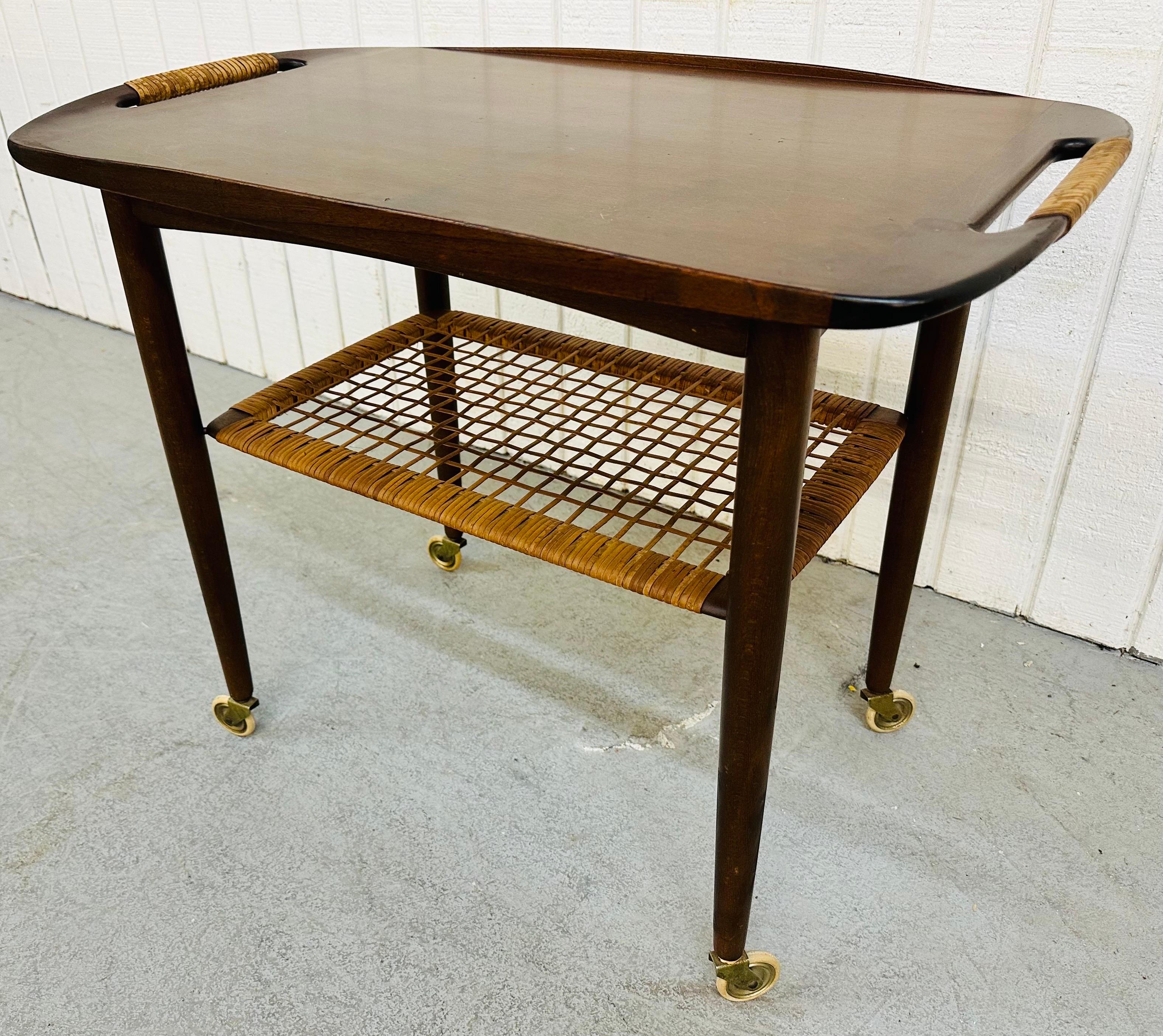 This listing is for a Mid-Century Danish Modern Walnut Bar Cart. Featuring a walnut top with woven handles, a woven bottom tier for storage, four long walnut legs with original wheels, and a Red Cross Denmark stamp underneath. This is an exceptional