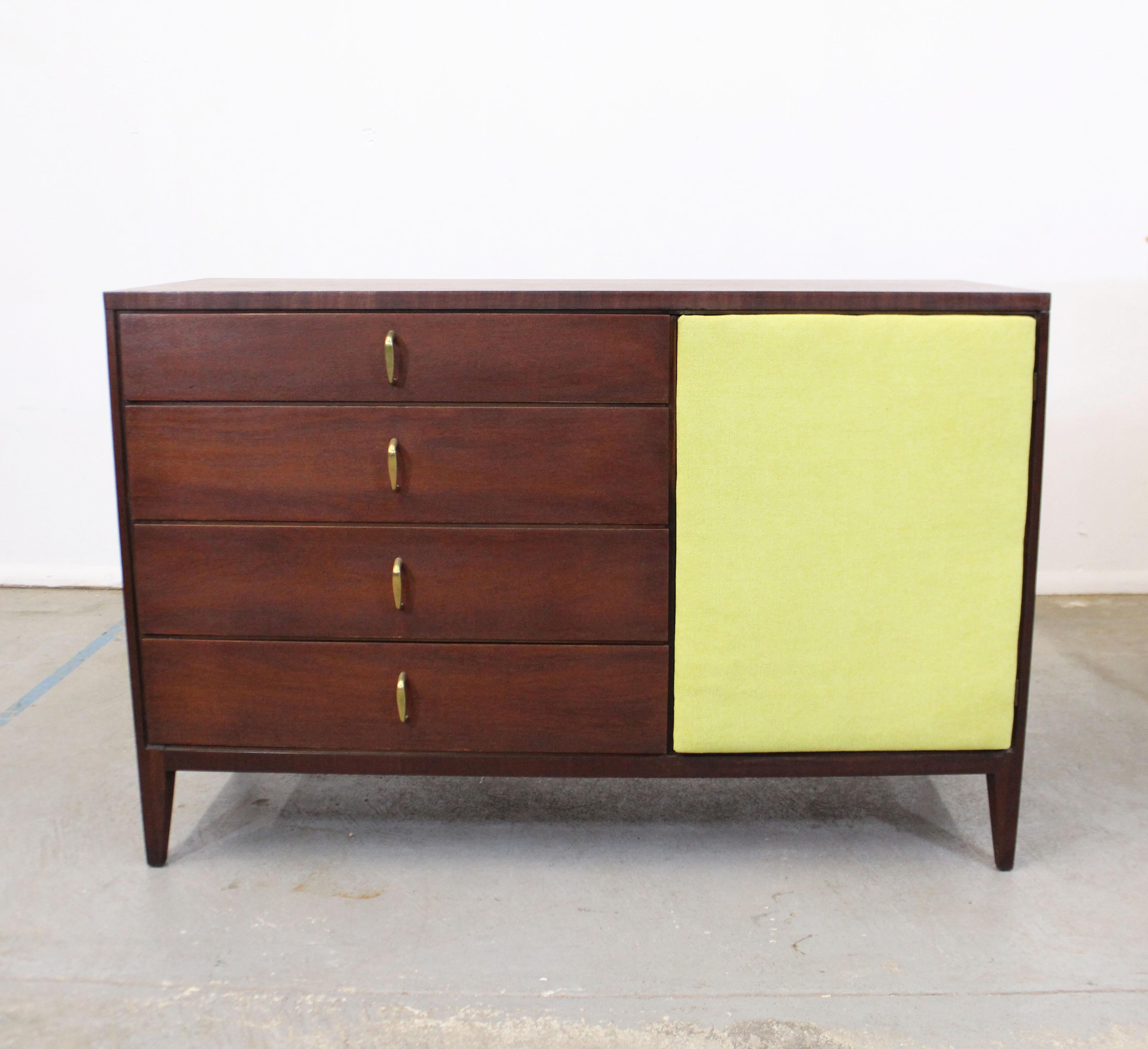Offered is a vintage Mid-Century Modern credenza. This is a beautiful mahogany credenza with a walnut stain that features an upholstered, magnetized push door. Has adjustable inner-shelving and four dovetailed drawers with brass pulls. It's in very