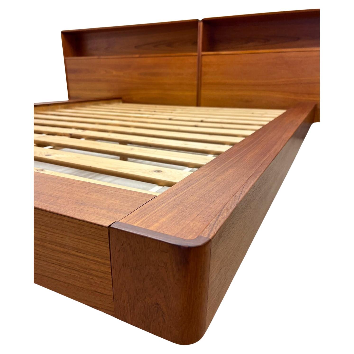 Stunning Mid century Danish Modern Teak Platform Queen Size Bed with headboard by Westnofa. Beautiful Platform bed that sits on a platform base with a long headboard with shelf storage. Has solid wood slats and teak sides and footboard. Made in