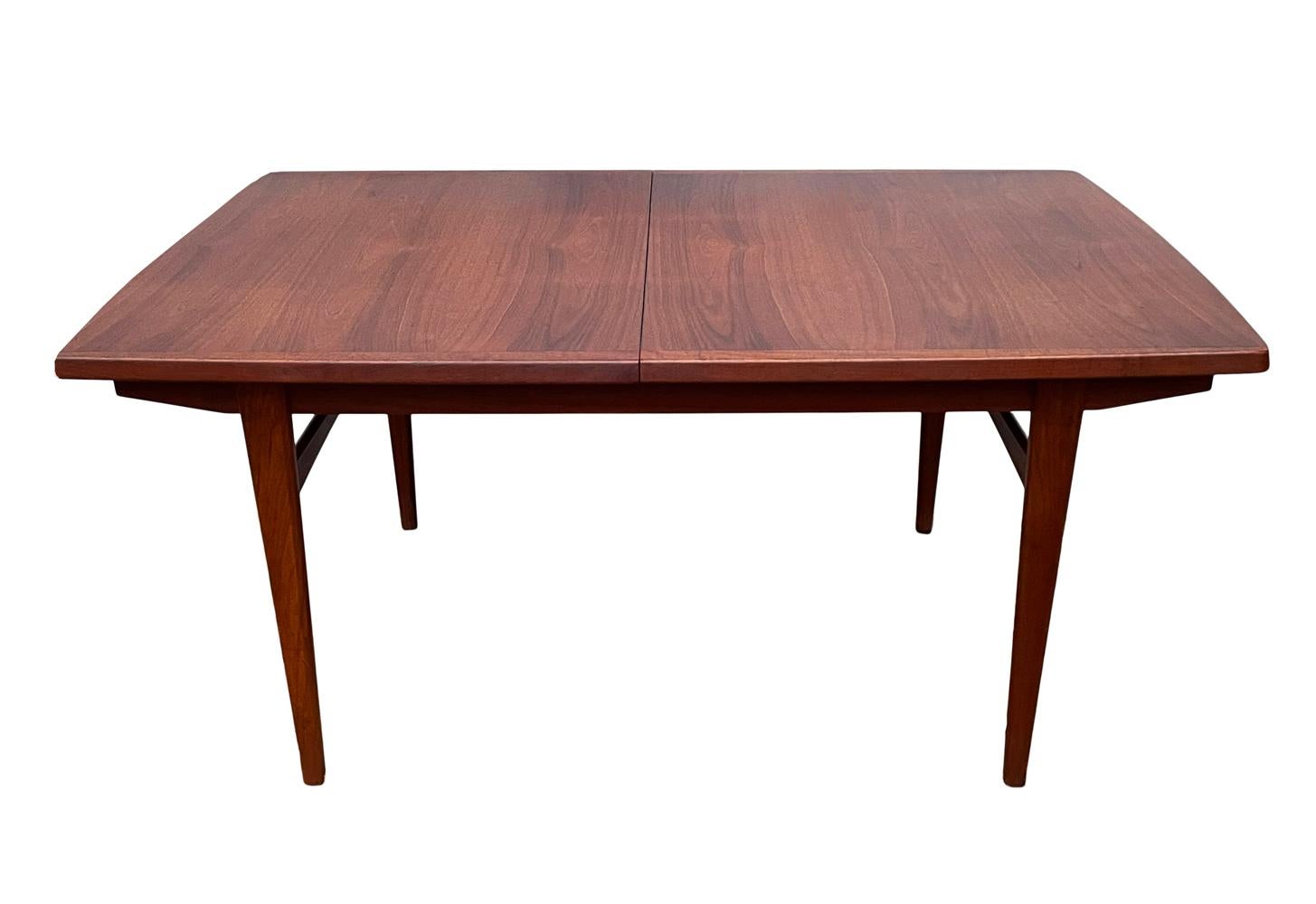 A large rectangular dining table from Denmark circa 1960's. It features beautiful teak wood construction. Included is 2 extension leaves that measure 18 inches in width. Total maximum length of table is 100.5 inches.