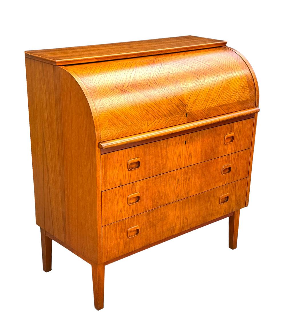 Una scrivania scandinava con piano a rotelle di bell'aspetto, realizzata negli anni '70. È caratterizzata da un bellissimo legno di teak e da un ampio spazio per riporre gli oggetti. 

Nello stile di: Finn Juhls o Arne Vodder.