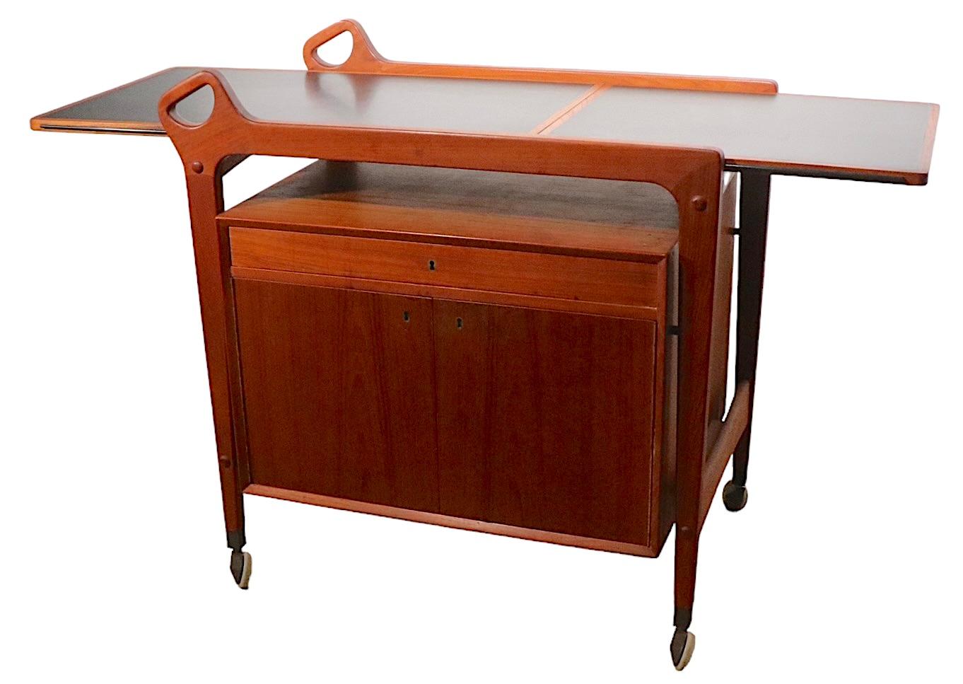 Exceptional bar, serving, cart in teak, with a black laminate top work surface. The cart features an extendable drop leaf surface creating plenty of room to mix drinks etc. Beneath the top is a lined pullout drawer, over a spacious two door cabinet.