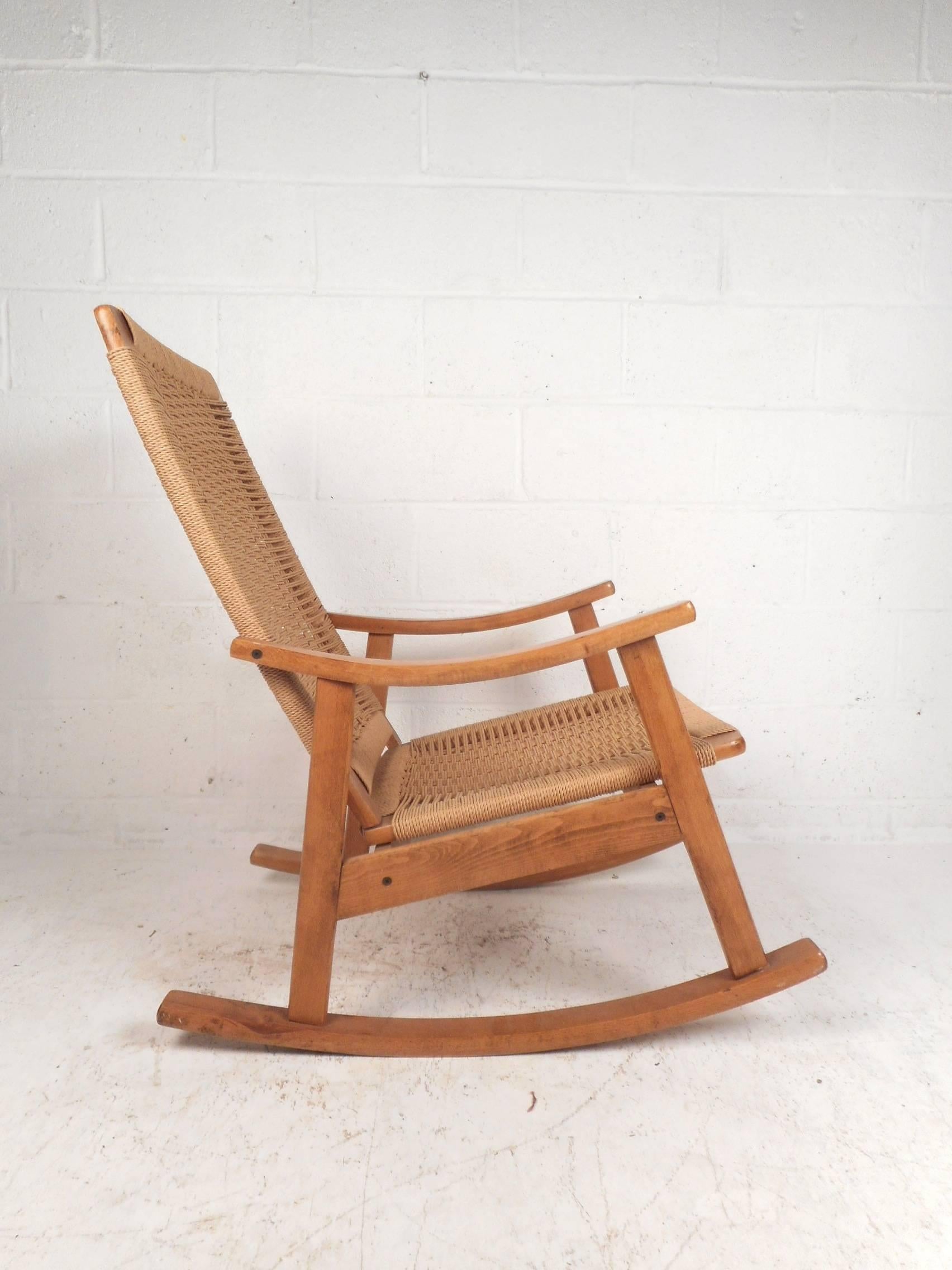 A gorgeous vintage modern rocking chair in the style of Hans Wegner. This stunning chair has a woven jute rope seat and back rest. An extremely comfortable and sturdy midcentury piece. The midcentury lines and blonde wood frame are sure to make an