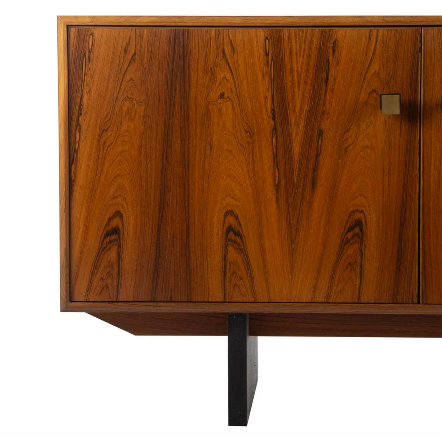 Mid century Danish modern rosewood 4 drawer credenza sideboard dresser cabinet. Has 4 drawers and 2 cabinet doors with brass pulls. Black Lacquer base. Beautiful Rosewood grain. Made In Denmark. Located in Brooklyn NYC.