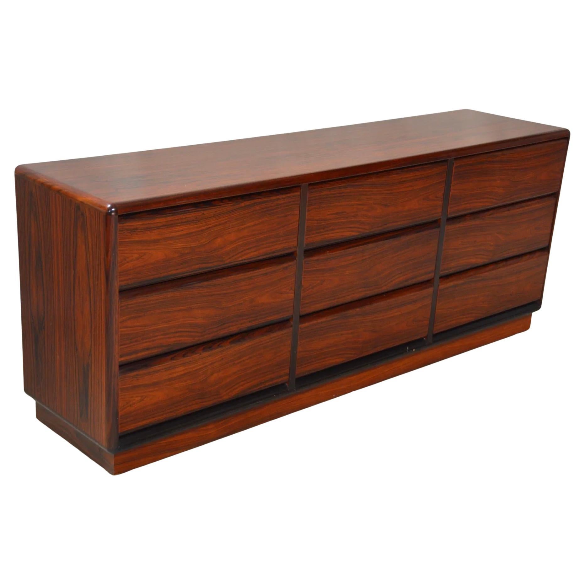 Very clean mid-century Danish modern rosewood 9 drawer credenza or dresser. All drawers slide smooth on metal glides with stops. Beautiful Rosewood grain. Rounded corners on a rosewood base. Made In Denmark labeled on back Brouer Mobler. Located in