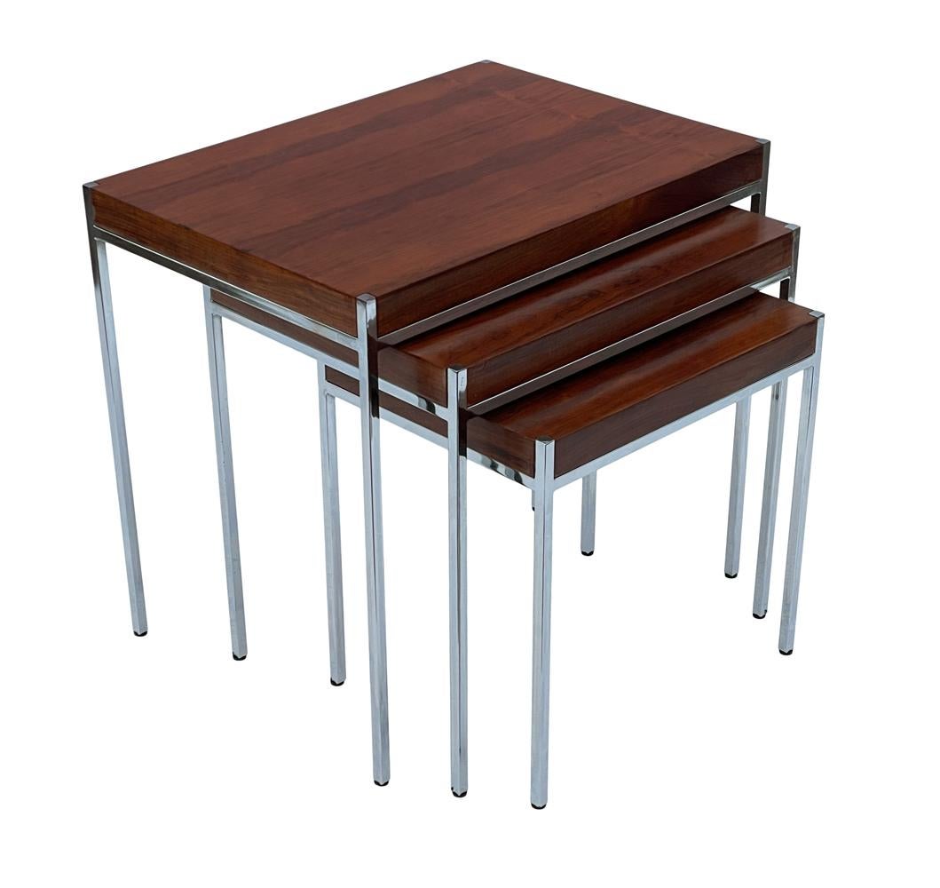 A sleek and modern set of nesting tables circa 1960s. These feature gorgeous rosewood with thin modern chrome framing.