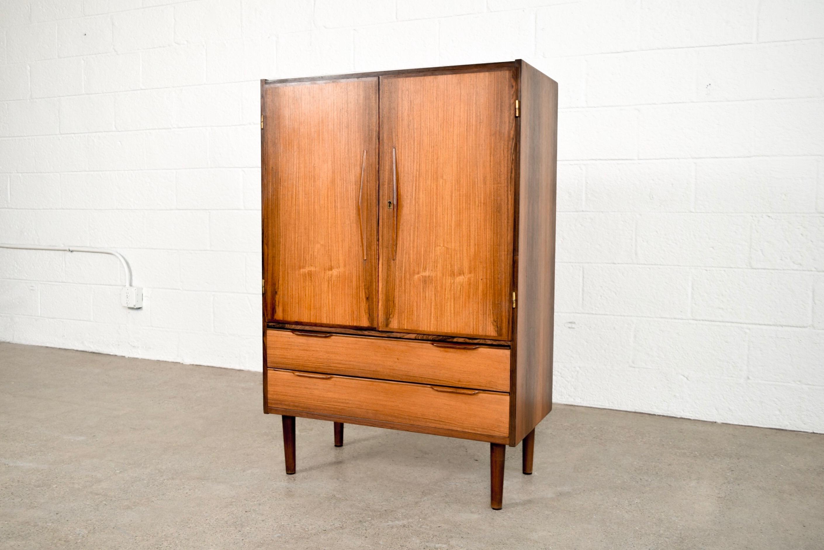 This striking vintage midcentury Danish modern bar cabinet in the manner of Arne Vodder or Finn Juhl and circa 1960 is expertly crafted from Brazilian rosewood with stunning wood grain. With a Classic Danish modern design it has clean Minimalist
