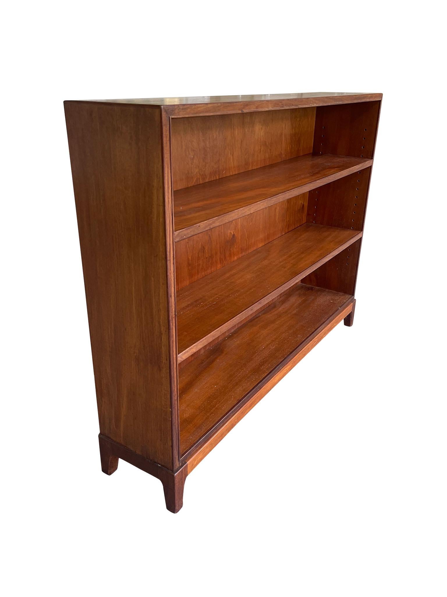 Lovely Mid-Century Modern Bookcase, designed by prolific Danish furniture designer Frits Henningsen. Crafted in versatile Rosewood, this open bookcase is designed with low, sleek legs and two adjustable shelves for flexibility and ease of use. The