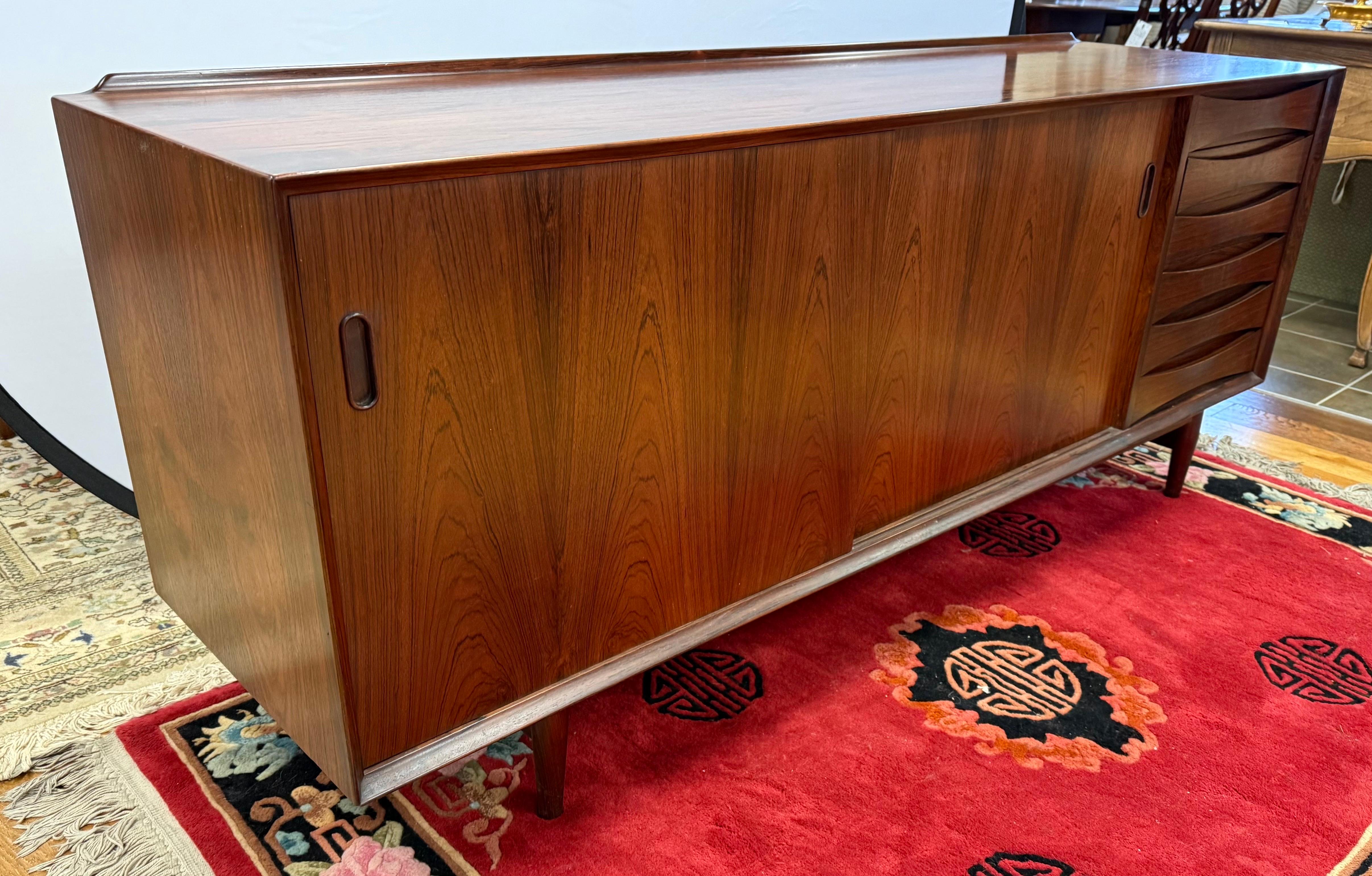 Elevate your interior with this exquisite mid-century Arne Vodder credenza, a masterpiece of Danish modern design.
• Designer: Arne Vodder, renowned for his minimalist and functional aesthetics.
• Material: Crafted from rich rosewood, showcasing