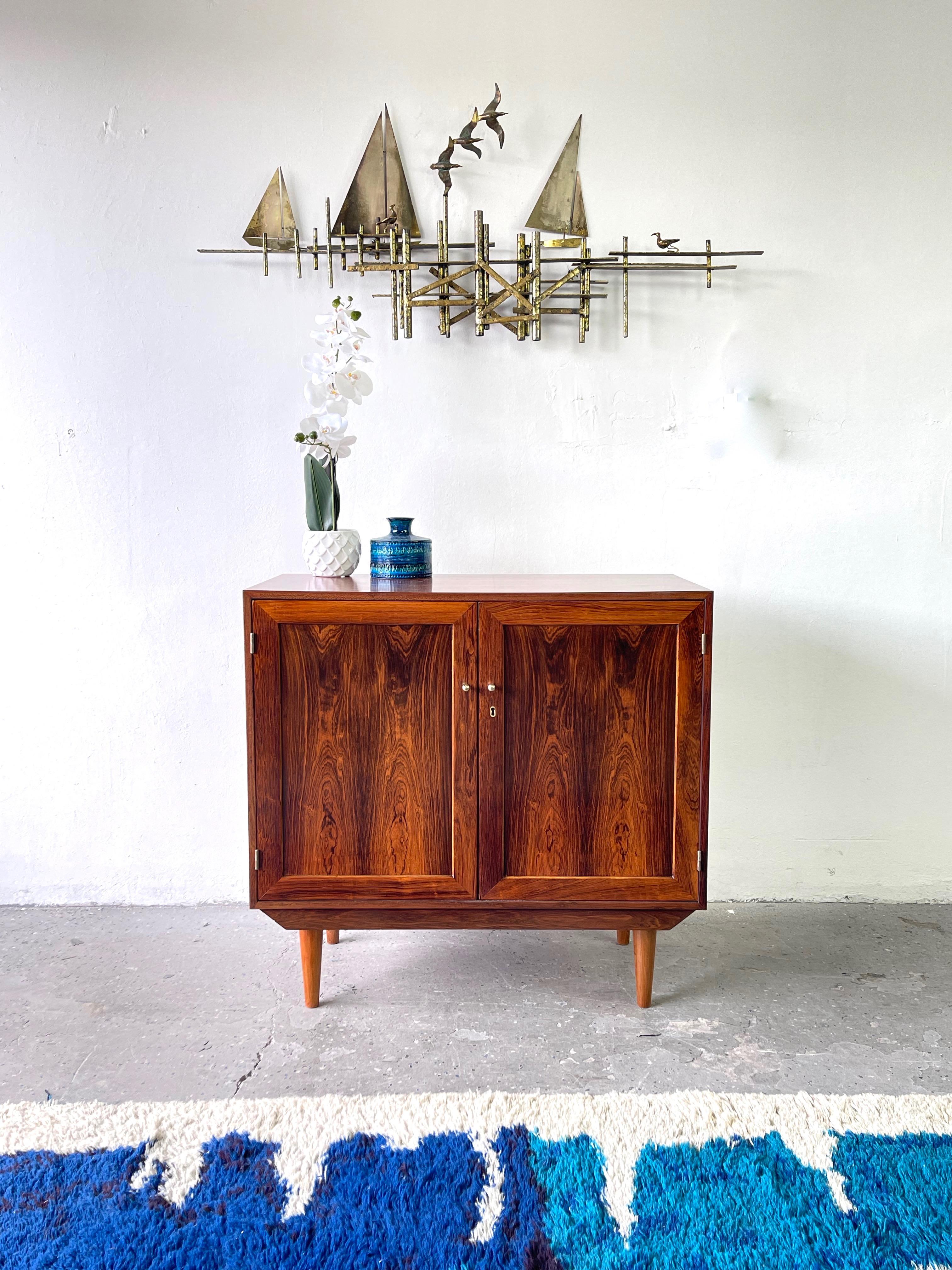 Super cool vintage Danish rosewood cabinet by Dyrlund. The cabinet has been restored, allowing the rosewood to be displayed in full glory. Dyrlund makes some of the finest case goods we have encountered with minimalist Scandinavian design enhanced
